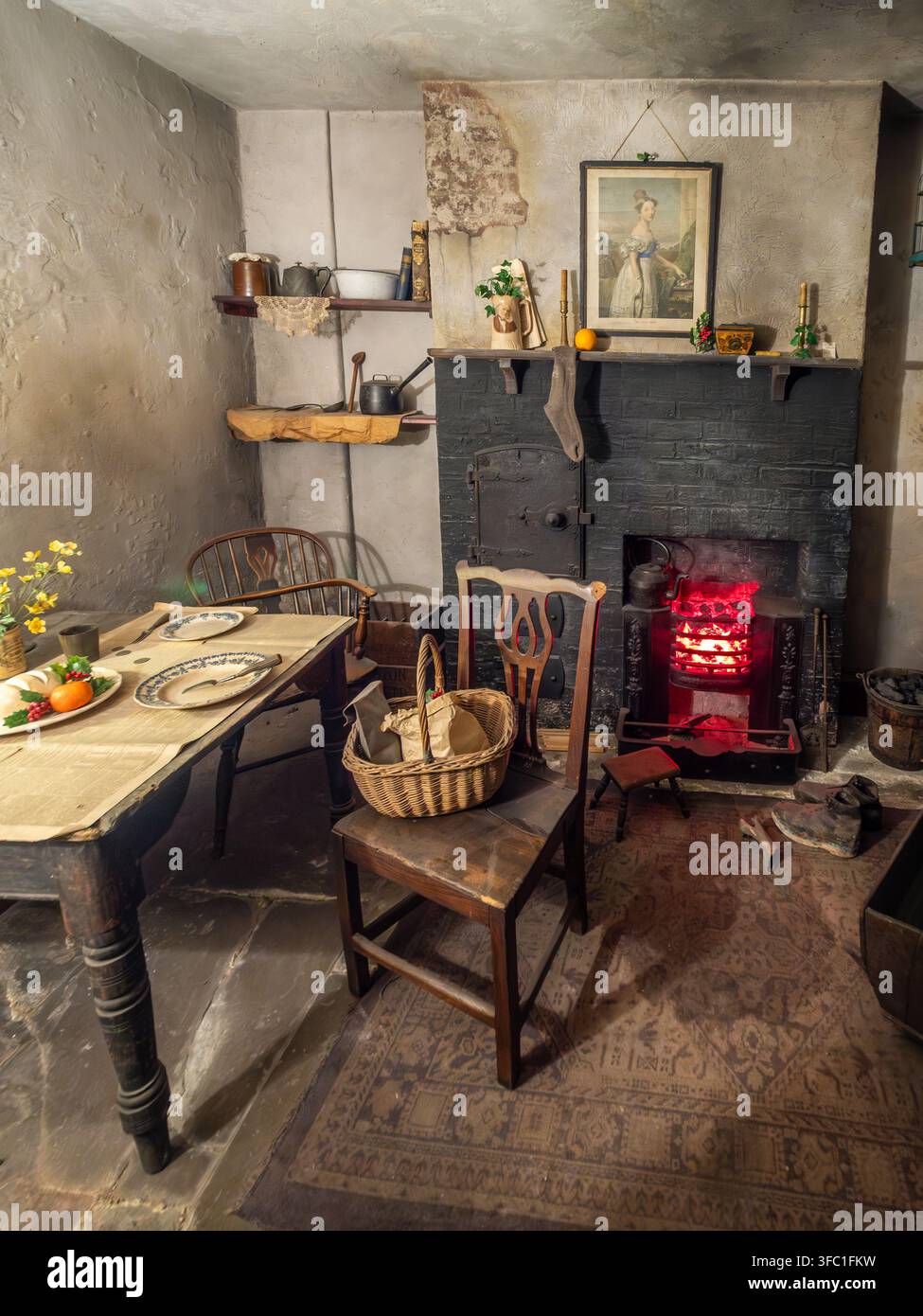 Cuisine modeste d'un cottage historique avec table, cheminée et objets ménagers au York Castle Museum à York, en Angleterre. Banque D'Images