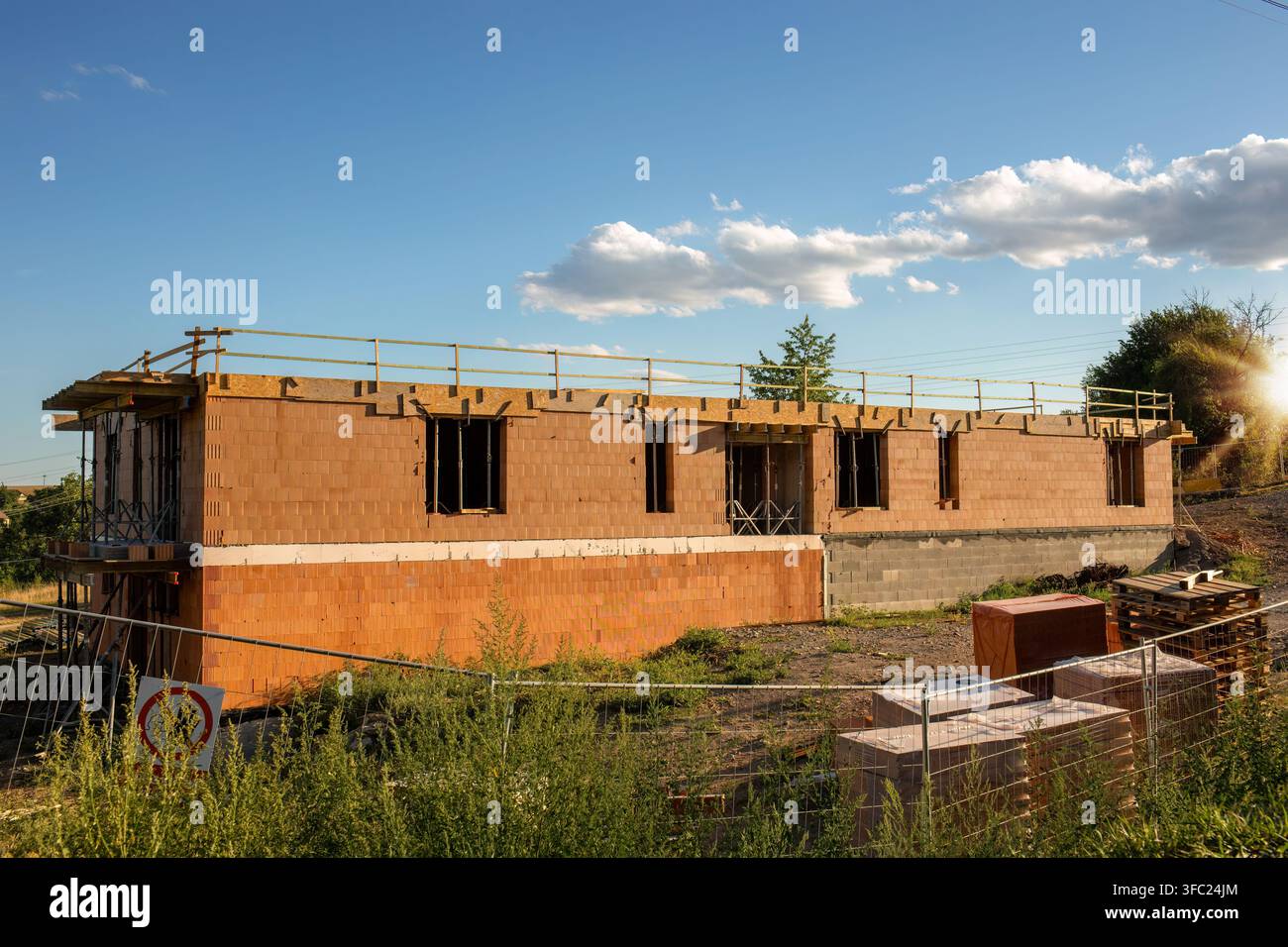 Chantier de construction d'une nouvelle maison familiale baignée d'une lumière chaude de coucher de soleil Banque D'Images