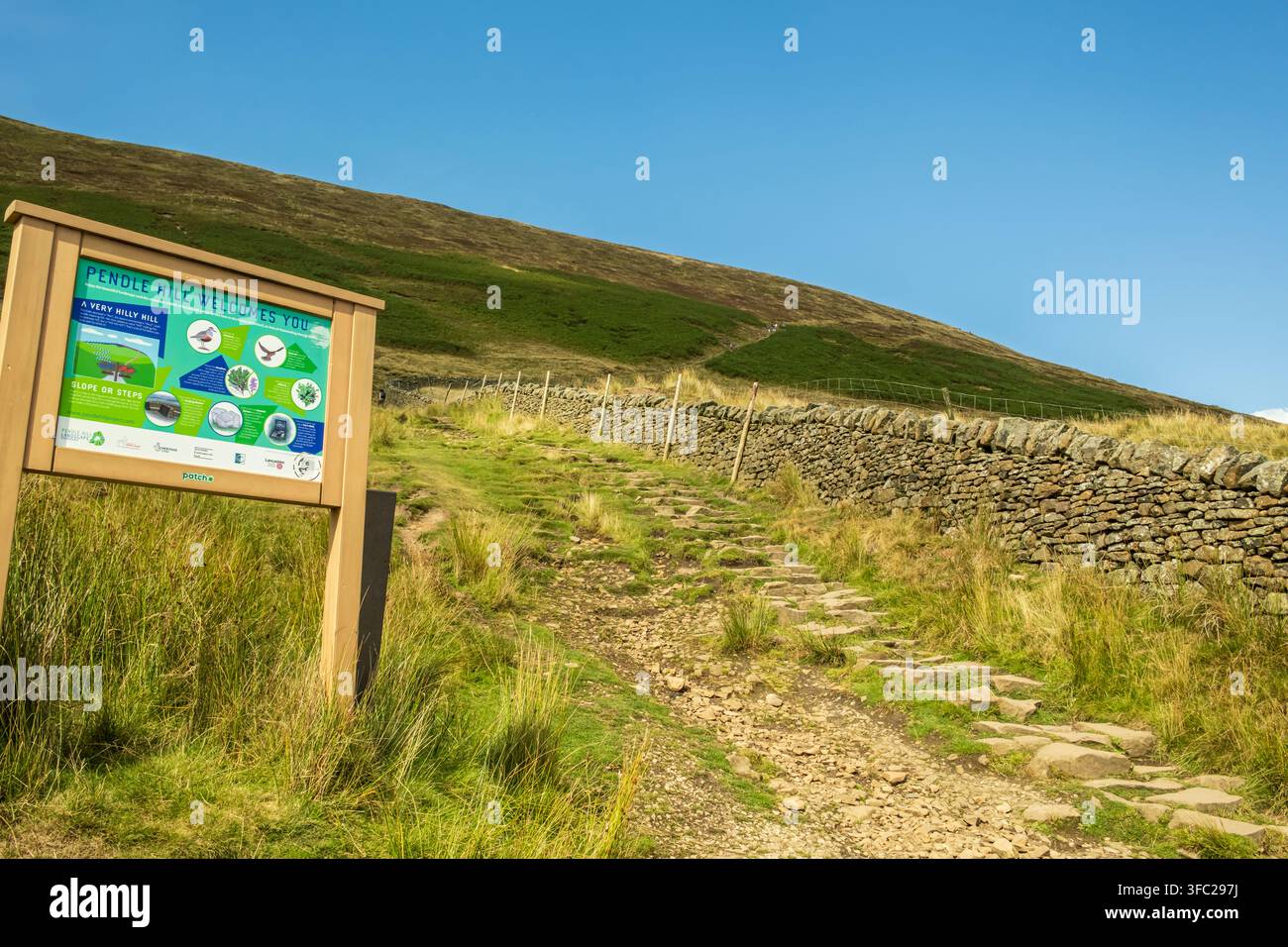 Un panneau d'information "Pendle Hill vous souhaite la bienvenue" se trouve au début d'un sentier pavé de pierres menant aux pentes herbeuses de Pendle Hill dans le Lancashire Banque D'Images