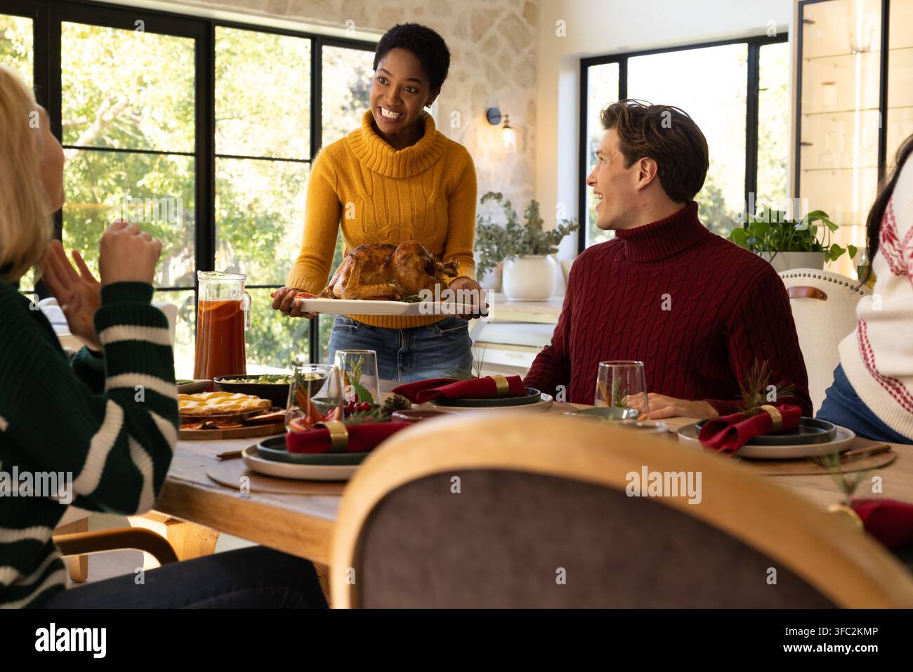 Famille divers servant une dinde rôtie sur une table à manger en bois à la maison avec une carafe Banque D'Images