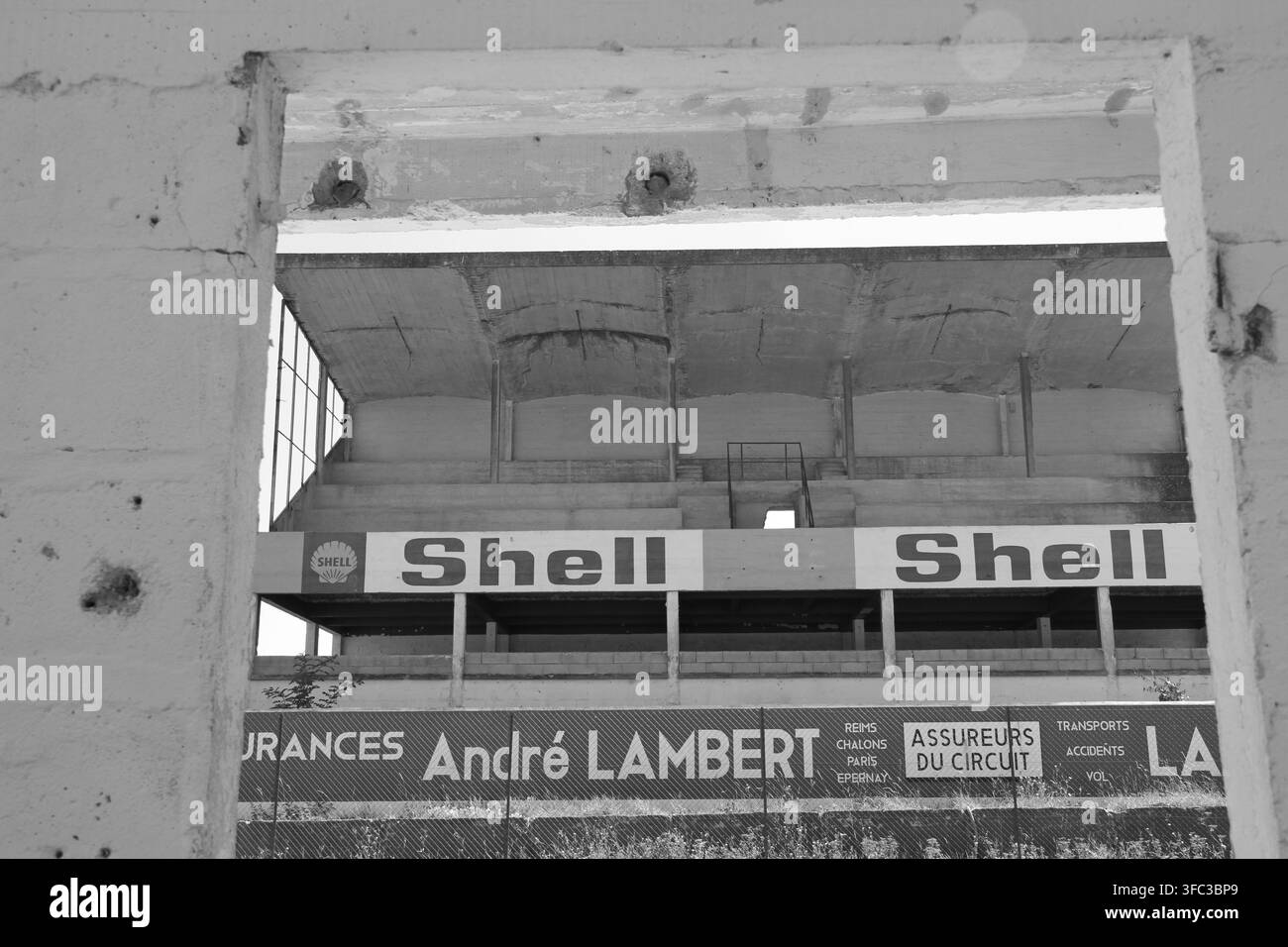 La tour d'horloge historique et les bâtiments abandonnés de la voie des stands recouverts de sponsorisations vintage sur l'ancien circuit de Formule 1 de Reims-Gueux en France Banque D'Images