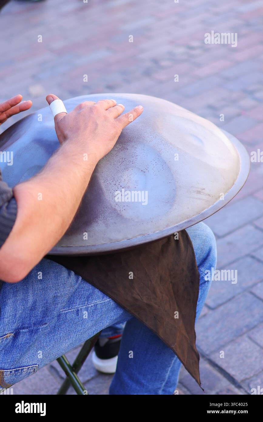 Musicien de rue jouant un tambour handpan en plein air, gros plan sur les mains exécutant sur un instrument de percussion en métal. Banque D'Images