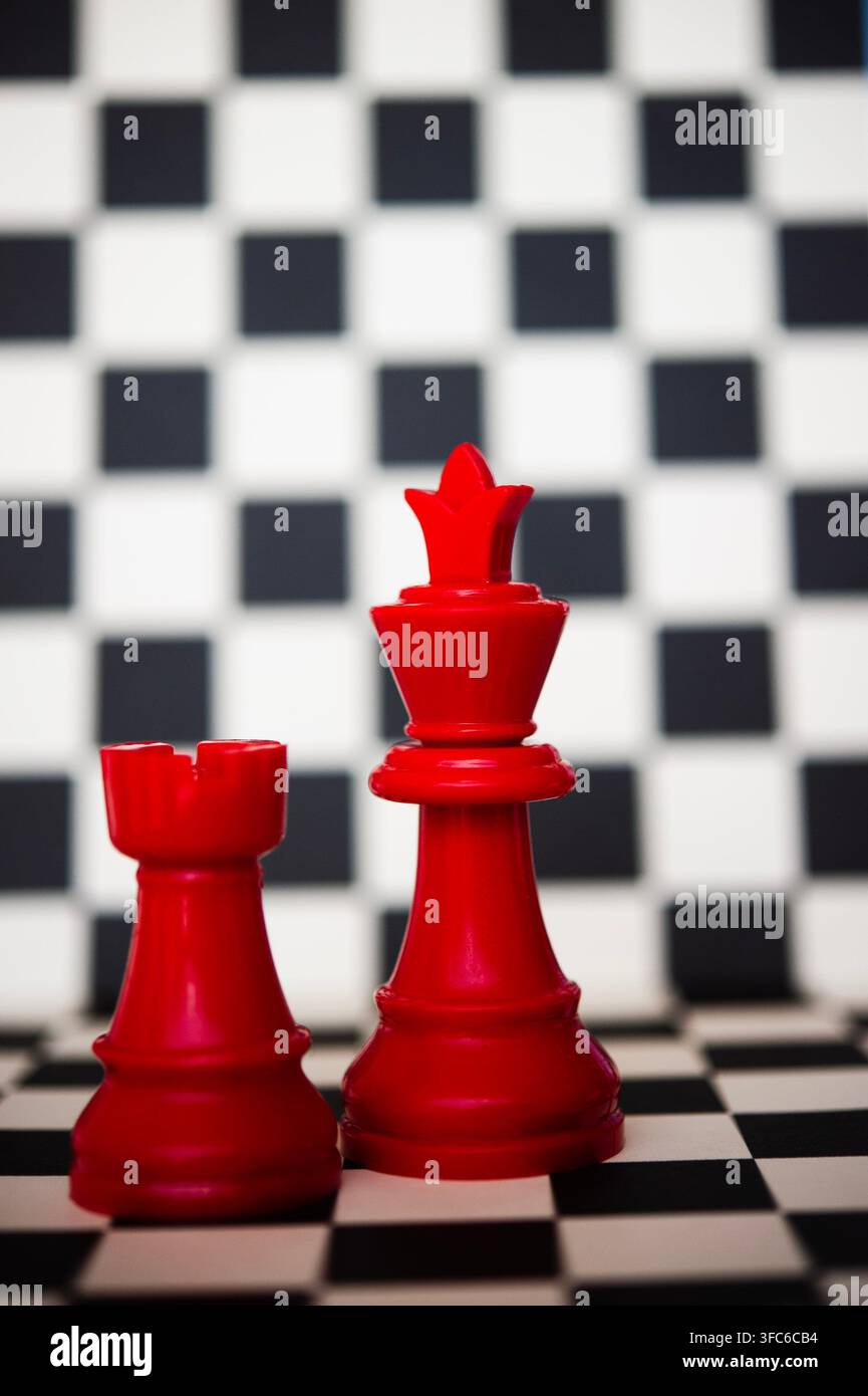 Pièces d'échecs rouges (tour et roi) debout ensemble sur un échiquier noir et blanc, suggérant le travail d'équipe, l'alliance, la stratégie et le pouvoir Banque D'Images