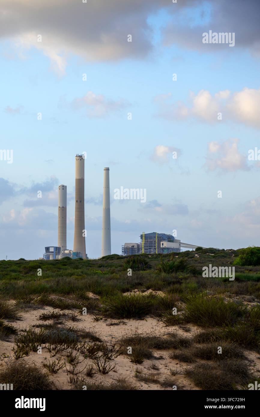 La centrale électrique de Zikim avec ses hautes cheminées se dresse sur la côte sablonneuse, illustrant la production d'énergie industrielle au milieu d'un paysage de dunes naturelles Banque D'Images
