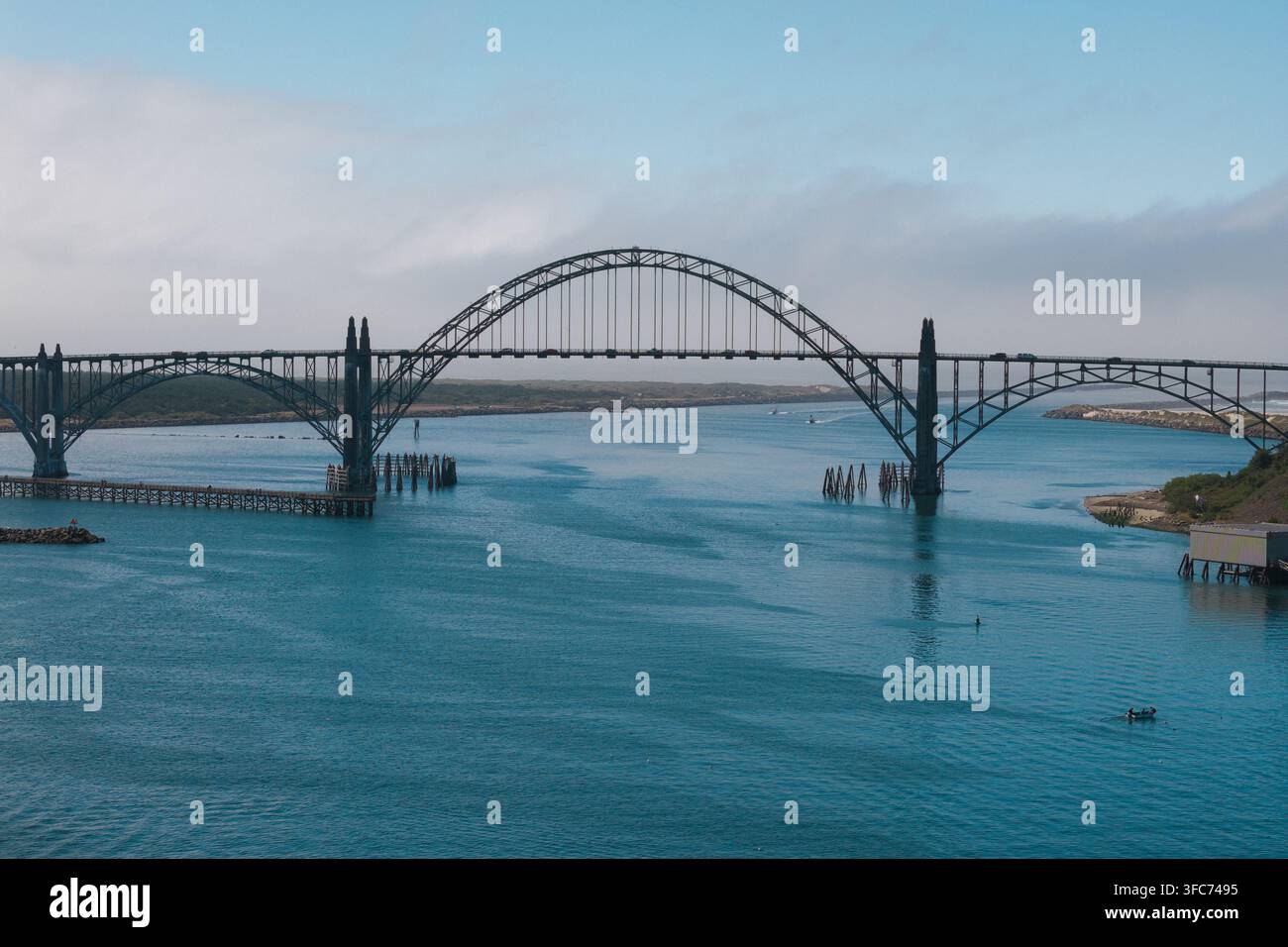 Vue aérienne du pont de Yaquina Bay enjambant les eaux bleues de la baie avec des collines côtières et un ciel dégagé à Newport, Oregon, États-Unis Banque D'Images