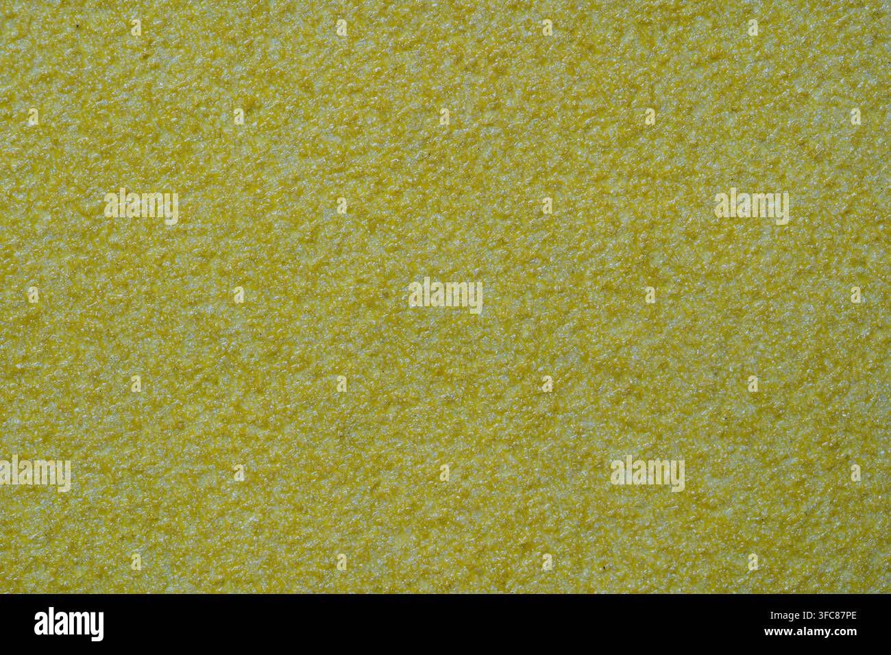 Texture de stuc ocré jaune sur un mur extérieur avec des grains fins. Surface rugueuse et sablonneuse semblable à du papier de verre en gros plan, motifs et textures conçus Banque D'Images