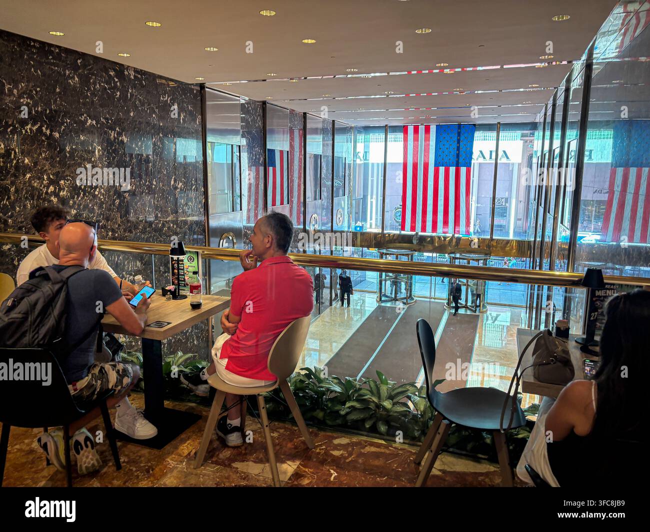 Les clients sont assis dans un café au mezzanine du Trump Tower, surplombant la Fifth Avenue et ses drapeaux américains. New York, New York, États-Unis, 7 août Banque D'Images