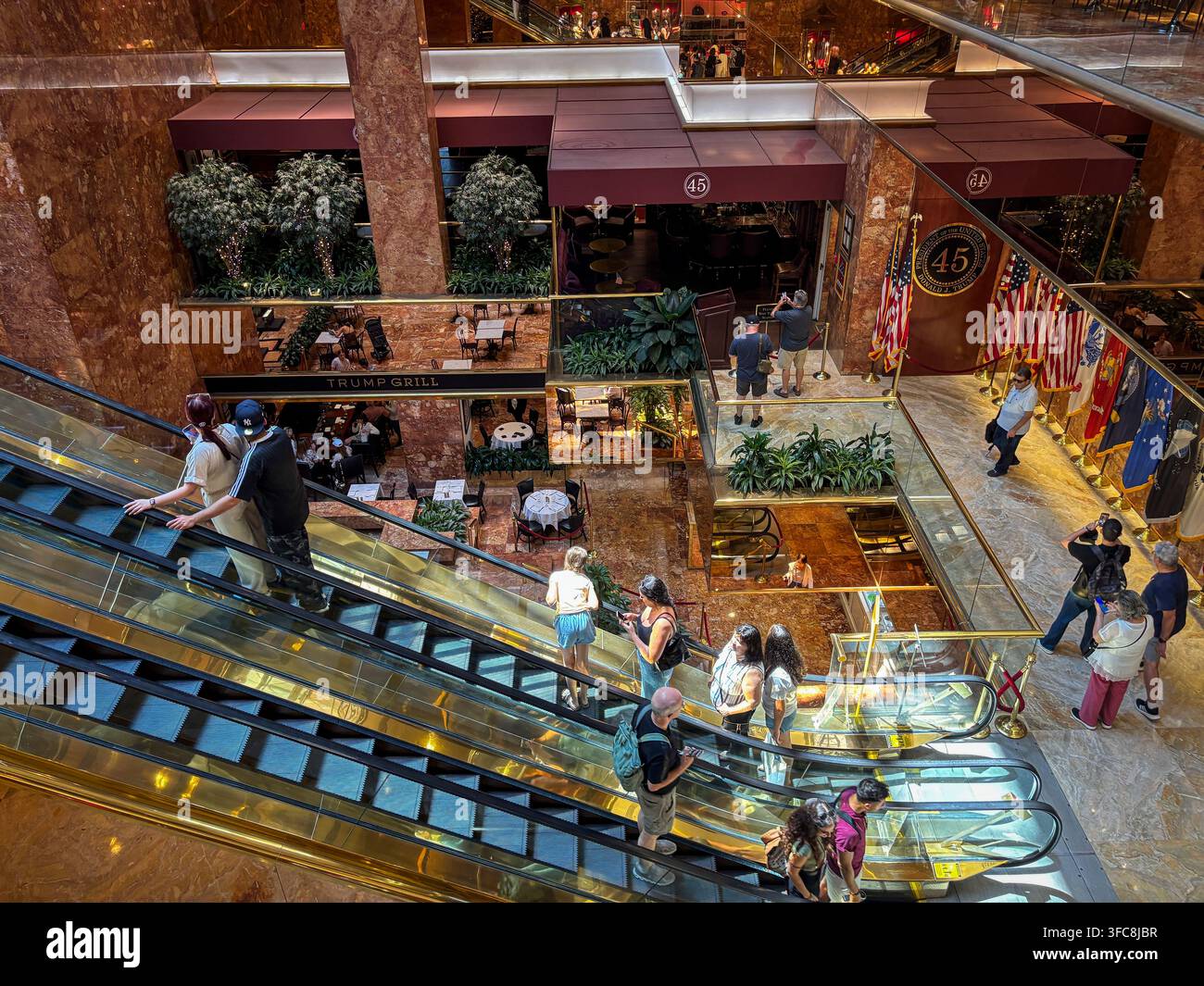 Visiteurs sur les escaliers mécaniques du Trump Tower, au-dessus du Trump Grill et des magasins de l'atrium. New York, New York, États-Unis, 7 août 2026. Banque D'Images
