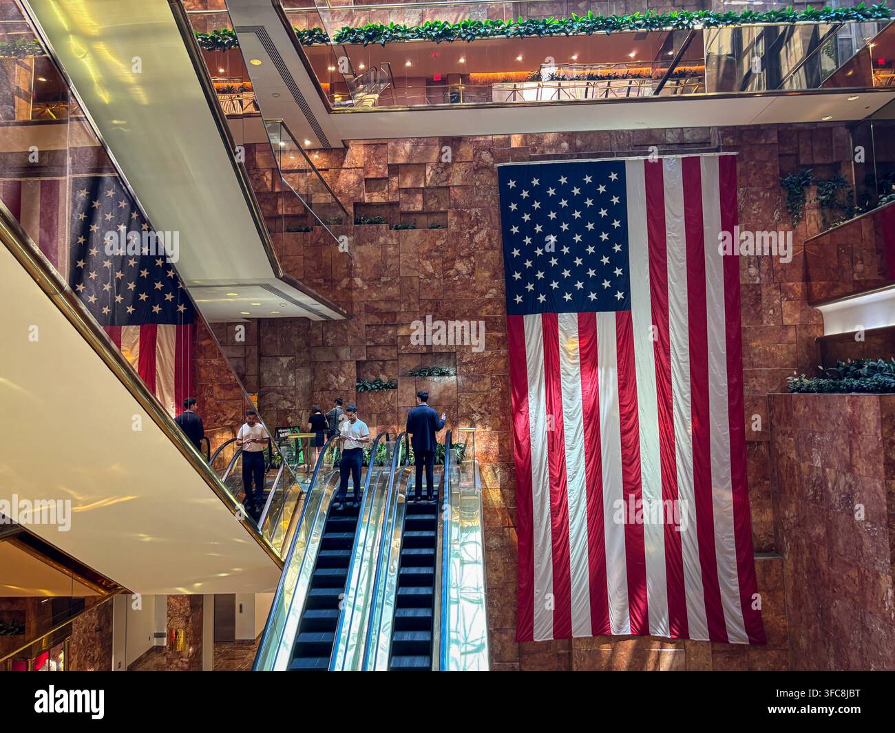 Des drapeaux américains sont suspendus aux murs en marbre rose Breccia Pernice de l'atrium du Trump Tower, au-dessus des escaliers mécaniques. New York, New York, États-Unis, 7 août Banque D'Images