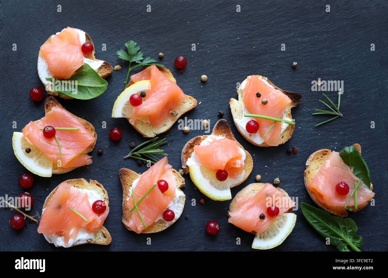 Amuse-gueules de saumon fumé gourmet avec fromage à la crème sur ardoise noire. Concept de finger food haut de gamme pour les célébrations de vacances, le catering de luxe, les menus de fête Banque D'Images