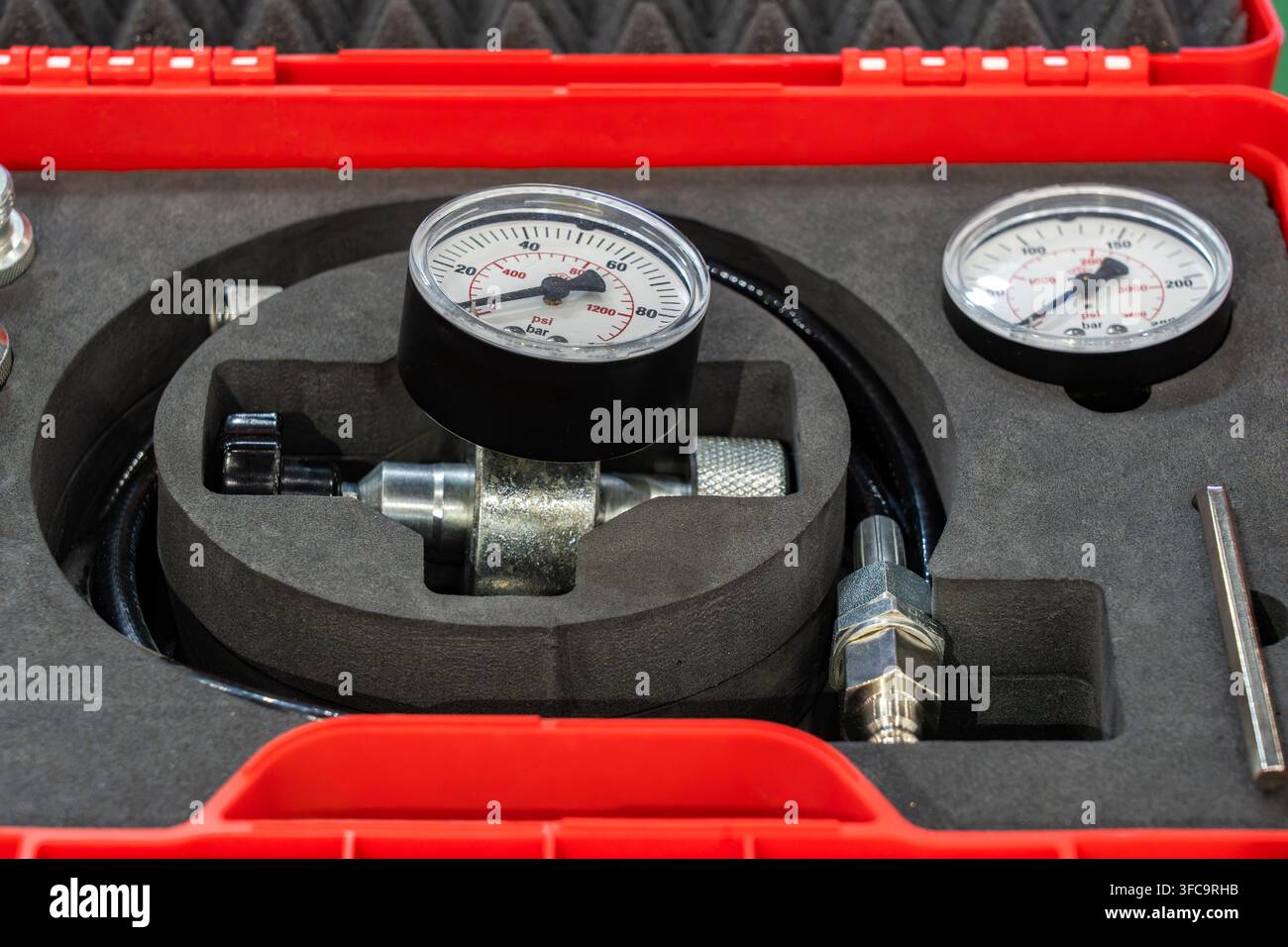 Kit de test hydraulique avec manomètres, raccords et tuyaux soigneusement organisés dans un étui de protection rouge Banque D'Images