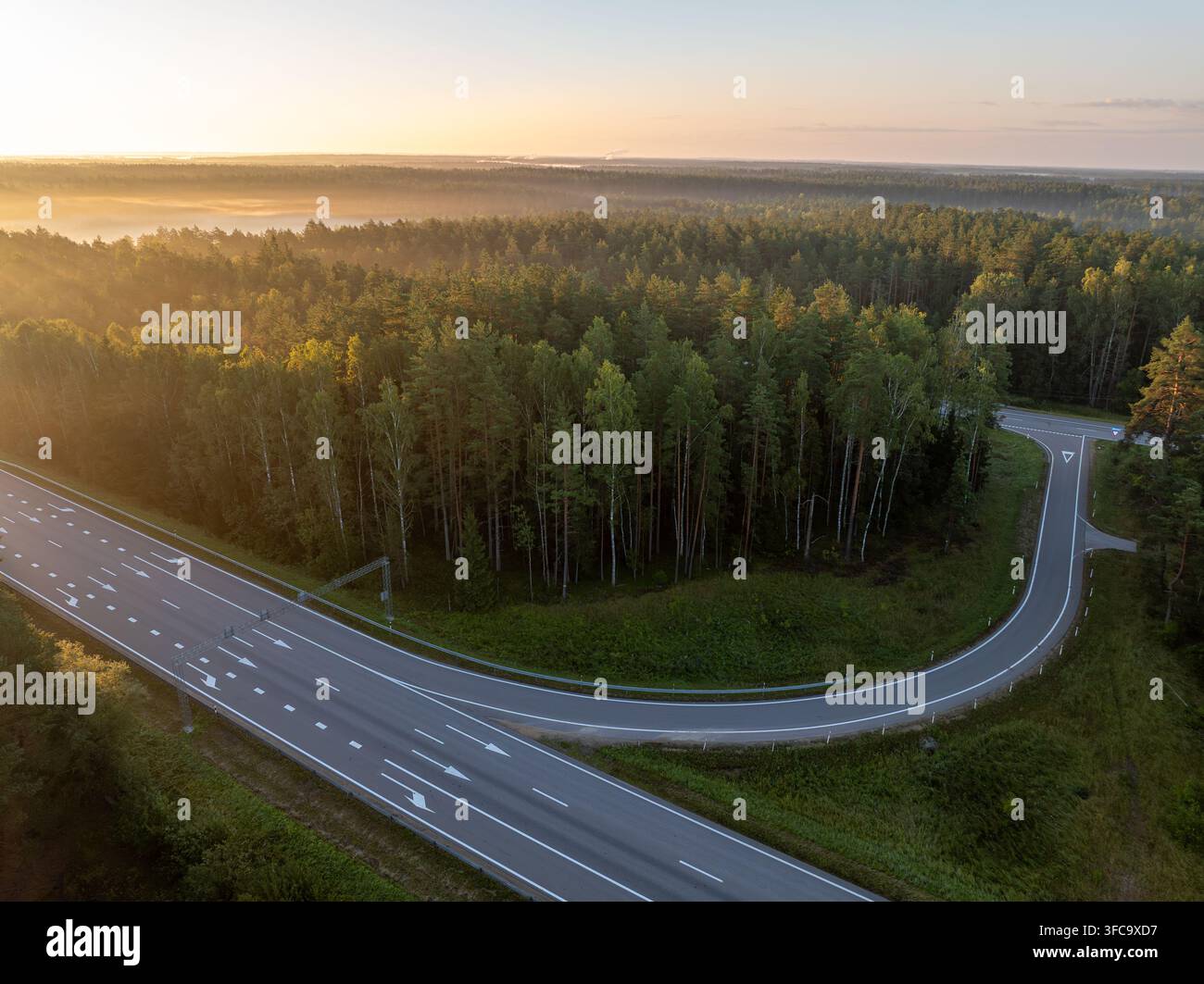 Vue aérienne de l'échangeur autoroutier A2 E77 près de Straujiupite, Lettonie, au lever du soleil avec forêt et brume matinale Banque D'Images