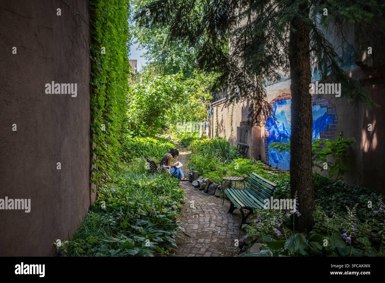 Femme assise dans un jardin communautaire paisible. Banque D'Images