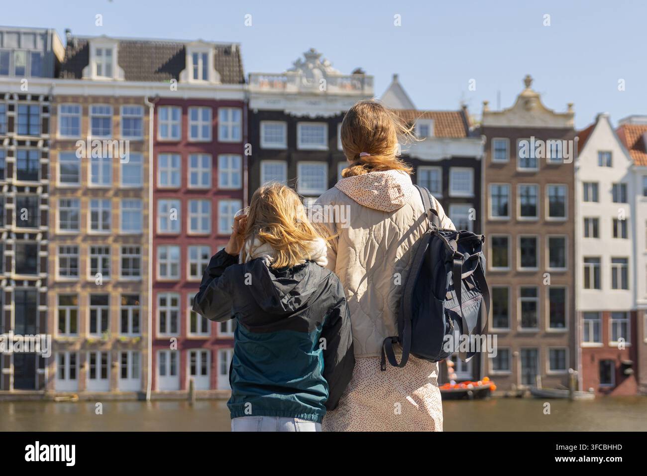 Une mère et sa fille se tiennent ensemble près d'un canal à Amsterdam. Elles regardent les bâtiments colorés et profitent de leur temps en voyageant en Europe. Banque D'Images