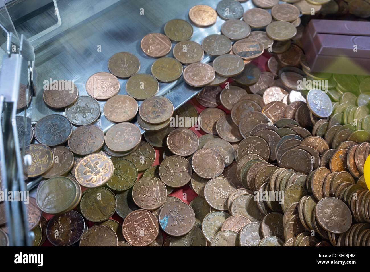 Grande collection de pièces de deux pence britanniques empilées dans une machine à sous d'arcade montrant des portraits de la reine Élizabeth II et distinctives Banque D'Images