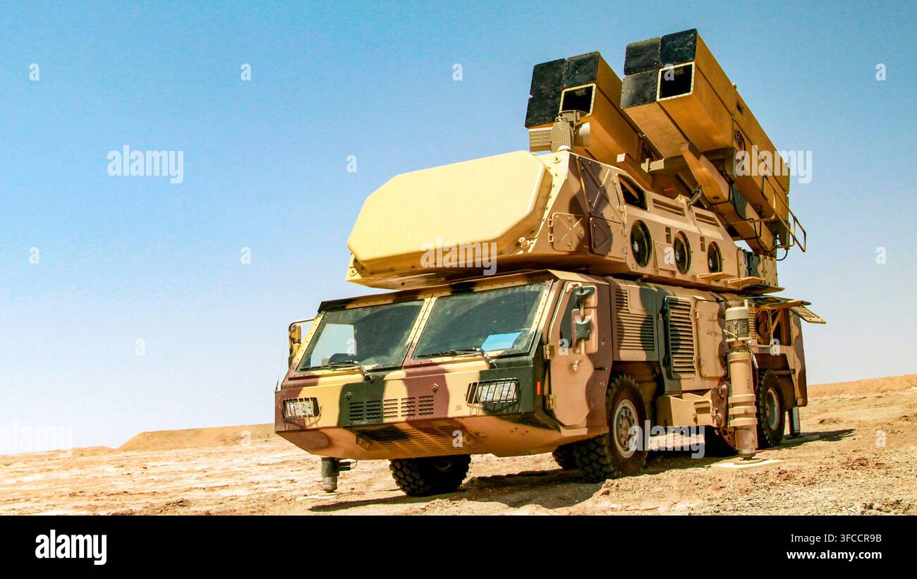 Systèmes de défense aérienne mobiles à missiles sol-air et unités de suivi radar montées sur des camions militaires dans un environnement désertique Banque D'Images