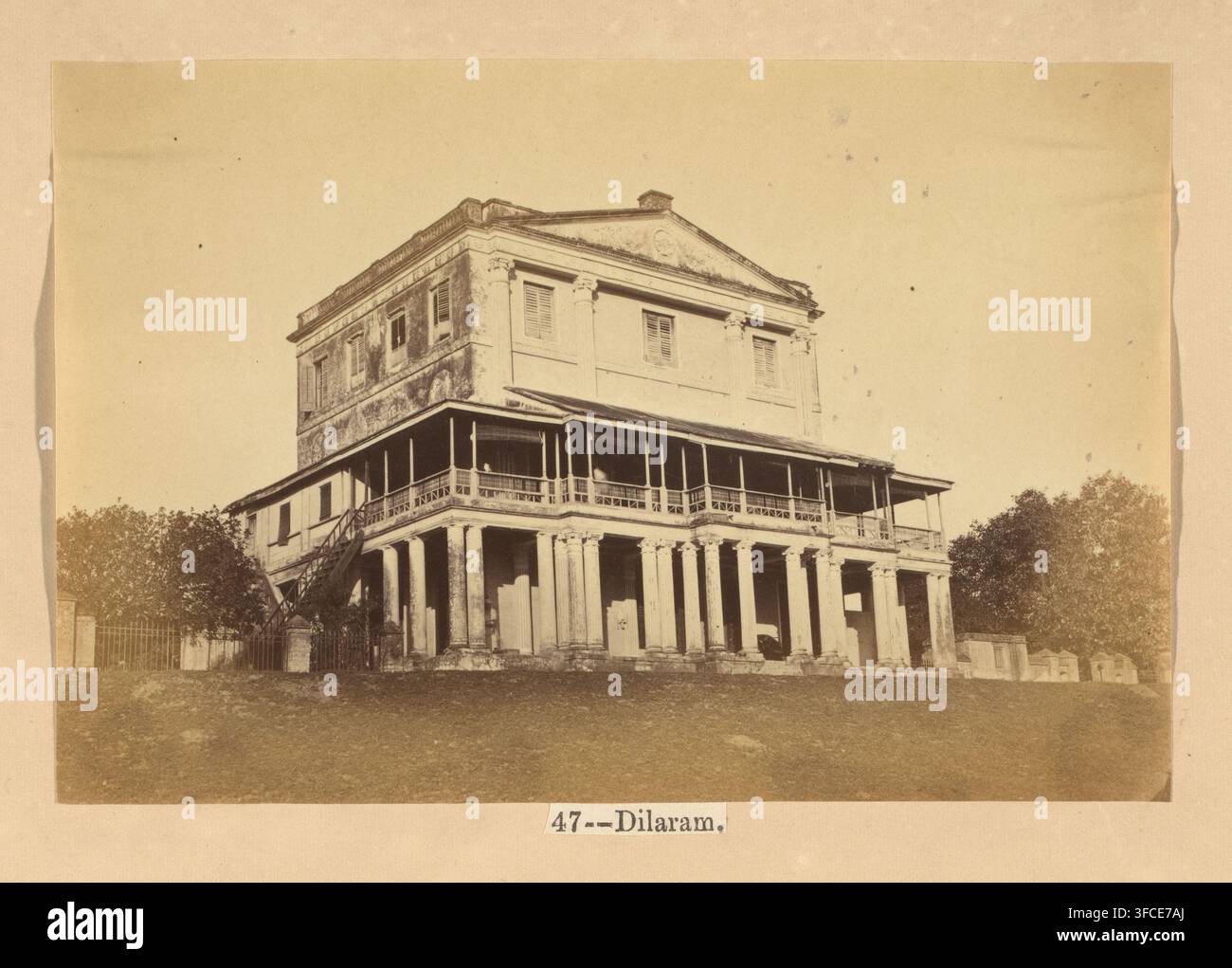 Dilaram, Vue d'une maison à Lucknow, photographie, page, numéro : '47', photographe : Darogha Ubbas Alli, Lucknow, c. 1864 - avant ou en 1874, Oudh, papier, impression à l'albumine, hauteur 102 mm x largeur 154 mm, boîtier., Une photographie sépia montre un grand bâtiment à deux étages avec un rez-de-chaussée surélevé soutenu par une rangée de hautes colonnes, une véranda supérieure avec une rambarde décorative enveloppant l'avant, et une section supérieure rectangulaire simple avec des fenêtres à volets et un fronton triangulaire au sommet ; une escalier extérieur en bois mène à la véranda d'un côté, la végétation entoure le bâtiment, et Banque D'Images