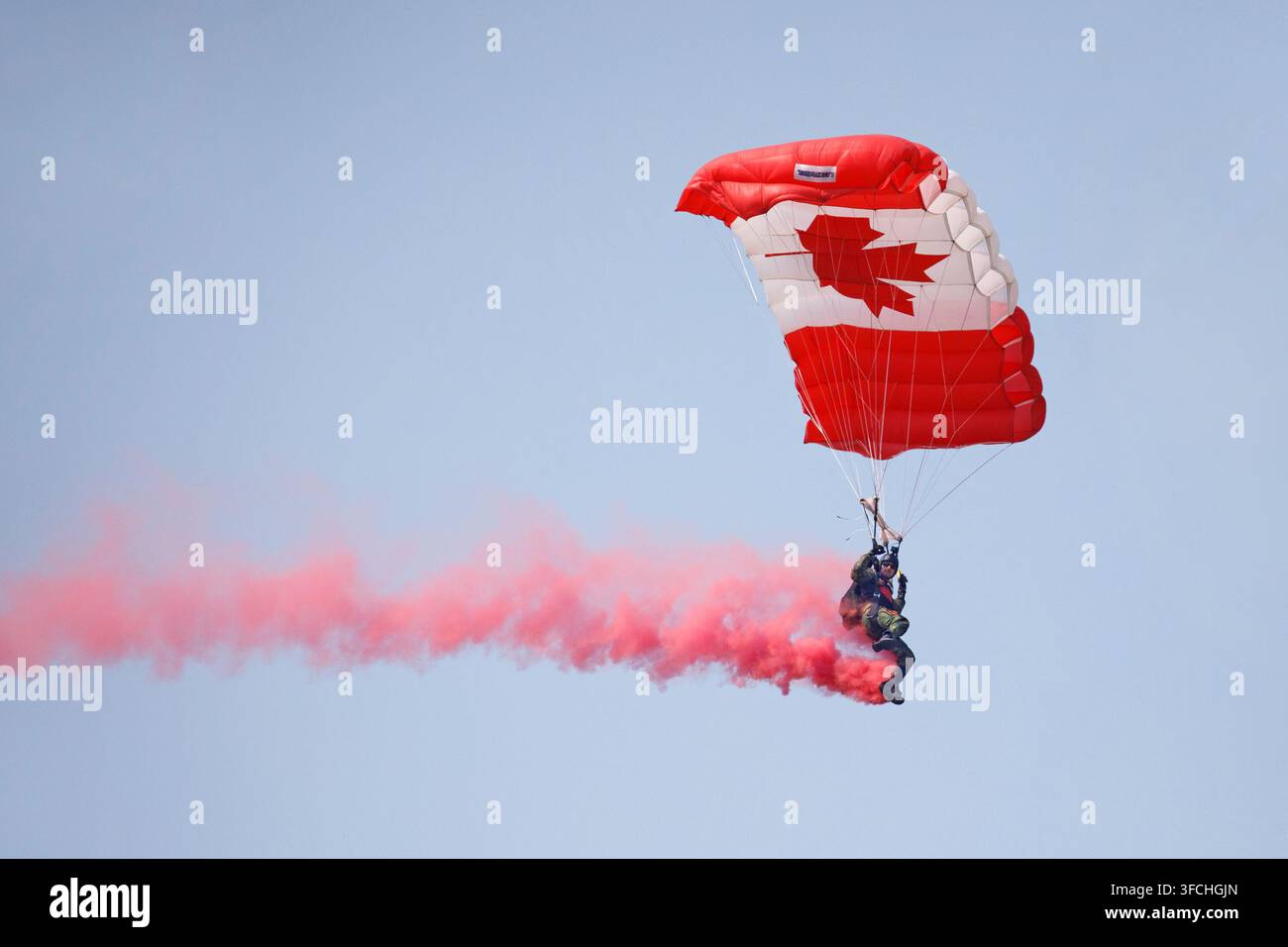 Parachutiste de l'équipe SkyHawks des Forces armées canadiennes effectuant un saut avec un drapeau national et une traînée de fumée. Red Deer Airshow, Canada Banque D'Images