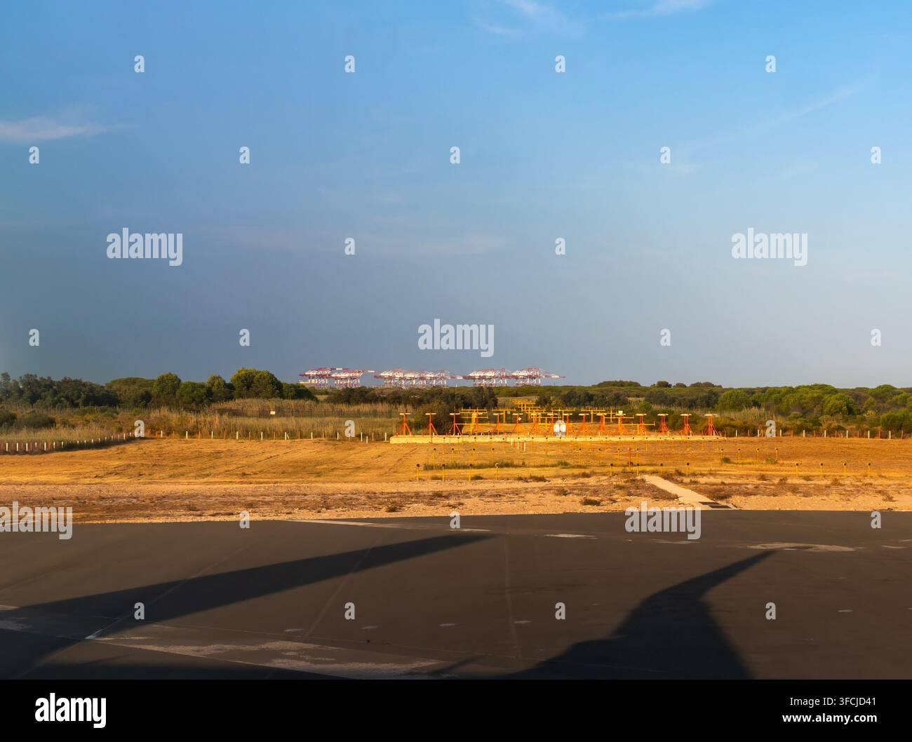 Aviation et infrastructure : Système d’éclairage d’approche de piste et grues portuaires au loin à l’aéroport Josep Tarradellas Barcelona-El Prat, Espagne Banque D'Images