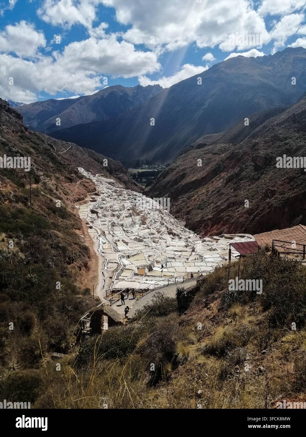 Vue panoramique des mines de sel de Maras à Cusco, au Pérou. Anciens bassins d'évaporation de sel dans la Vallée Sacrée sous des nuages dramatiques et des rayons de soleil. Banque D'Images