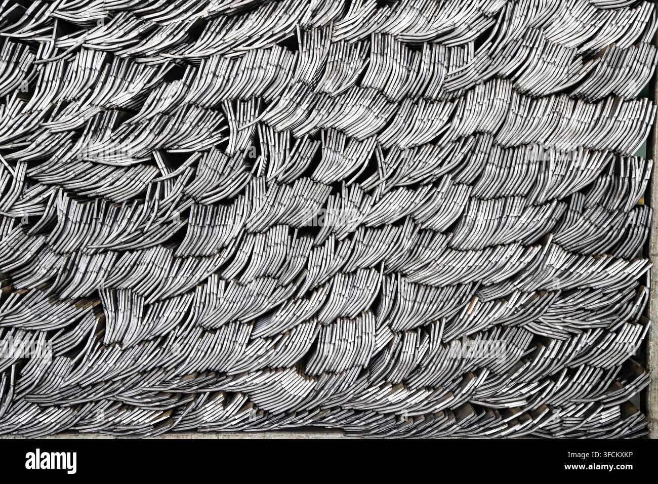 Photographie en gros plan très détaillée montrant des pièces métalliques allongées pour la fabrication d'outils, empilées dans un arrangement régulier et incurvé en couches. L'image Banque D'Images