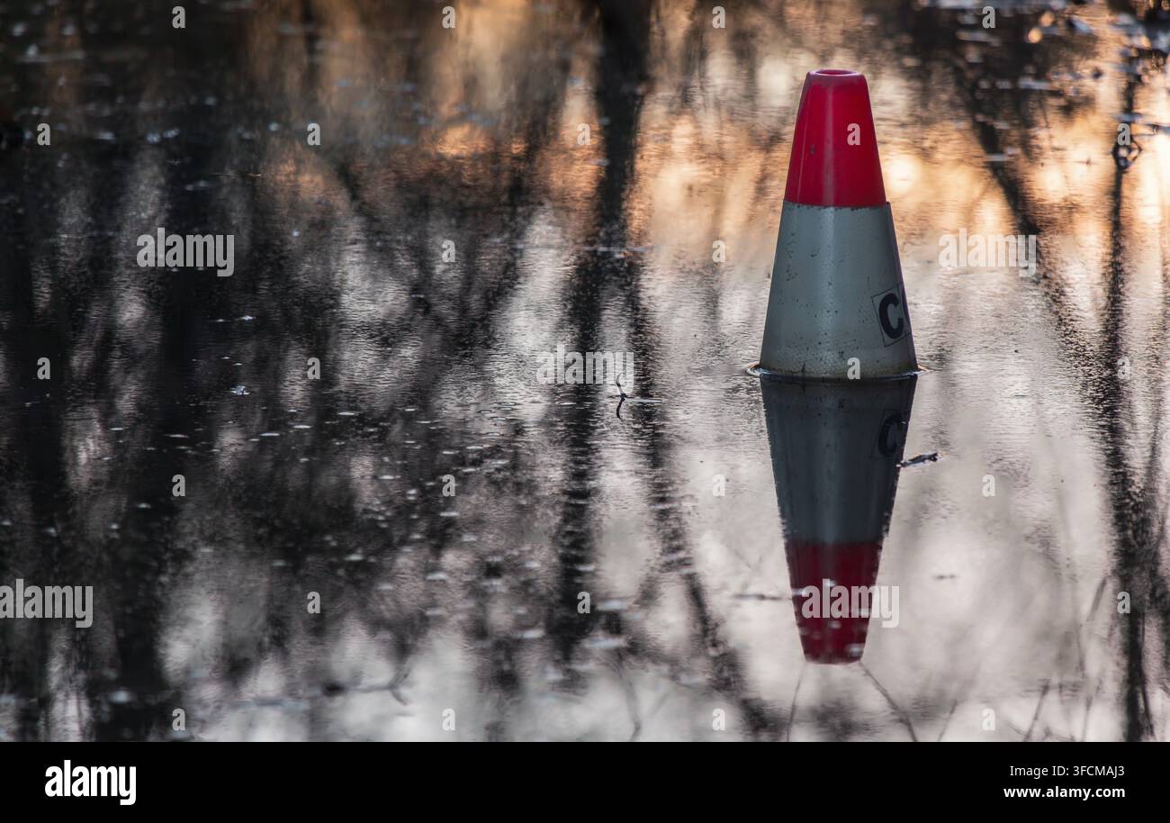 Cône de signalisation rouge et blanc submergé dans les eaux d'inondation du lac Trout au parc John Hendry à Vancouver, Colombie-Britannique. Banque D'Images