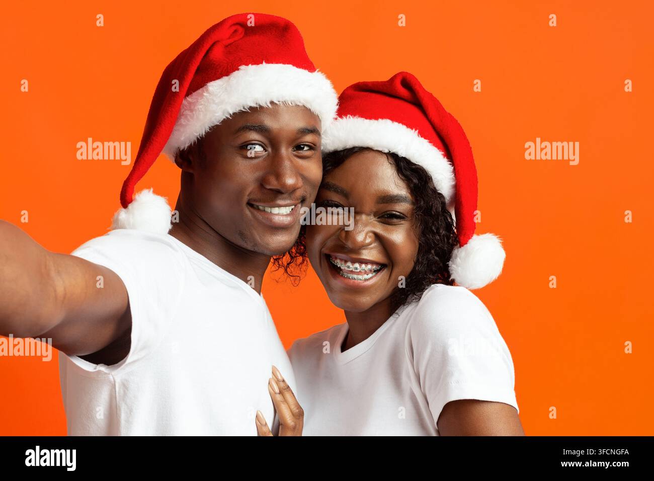 Magnifique homme noir et femme en chapeau de père Noël prenant le selfie Banque D'Images