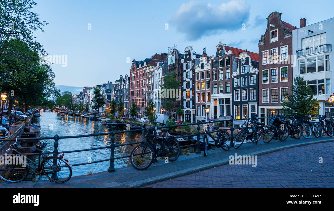 Vélos garés sur un pont au-dessus d'un canal d'eau à Amsterdam le soir Banque D'Images
