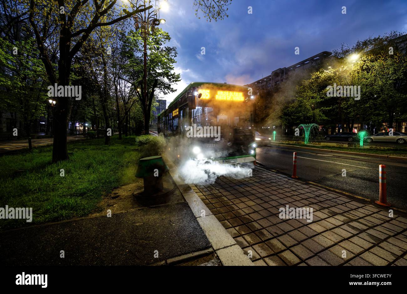 Véhicules sur le Bulevardui Unirii bordé d'arbres au crépuscule avec fontaines et éclairage coloré dans le secteur 1, Bucarest, Roumanie Banque D'Images