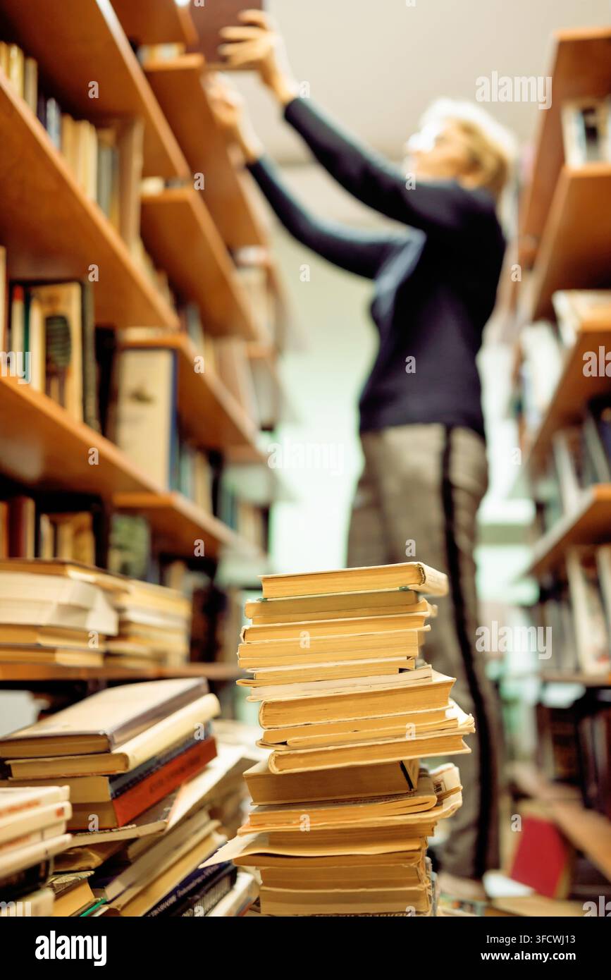 Une bibliothécaire dispose des livres sur les étagères de la bibliothèque. Banque D'Images