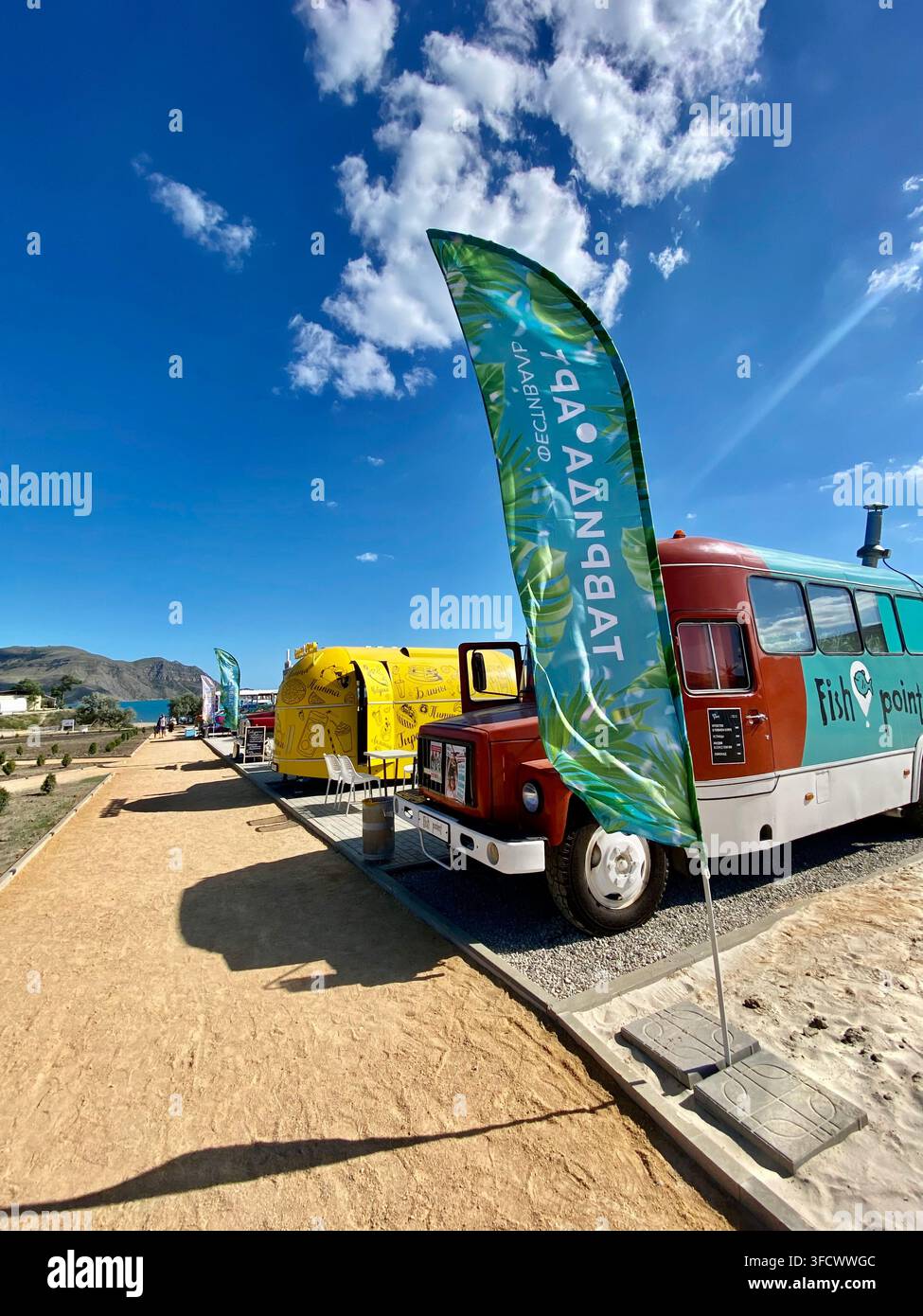 Crimée, Russie - 15 juillet 2022 : Des camions-restaurants colorés et des drapeaux publicitaires bordent la promenade côtière. - Image de stock capturée avec un smartphone