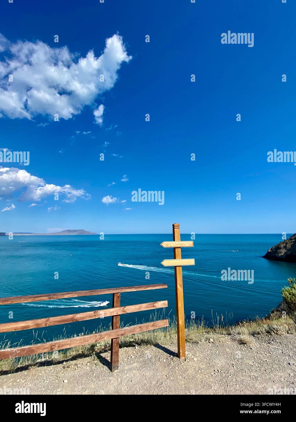 Les panneaux de signalisation en bois sur les sentiers surplombent une mer bleu vif sous un vaste ciel d'été - Image de stock capturée avec un smartphone