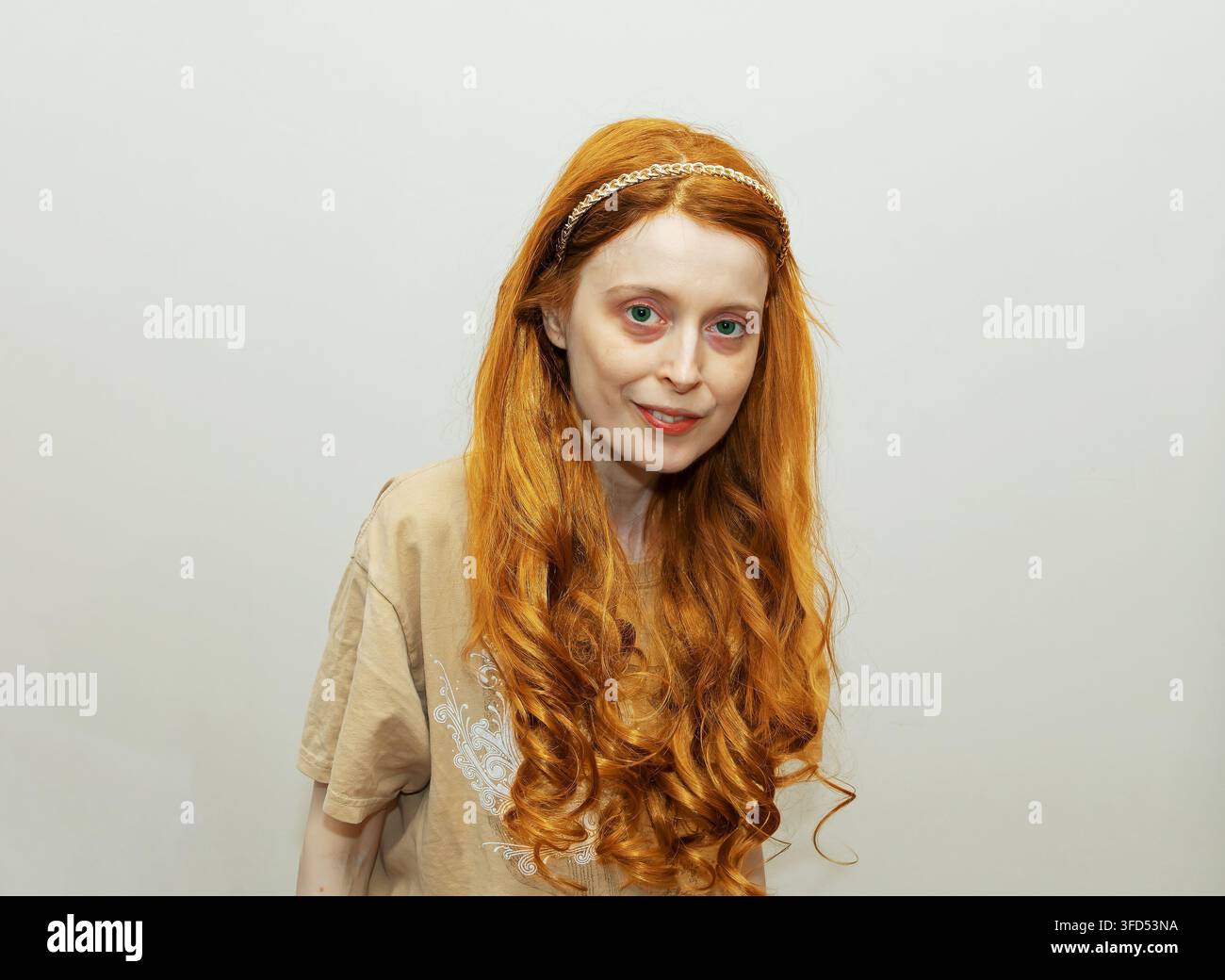 Jeune femme magnifique aux cheveux bouclés et roux souriant dans un intérieur domestique Banque D'Images