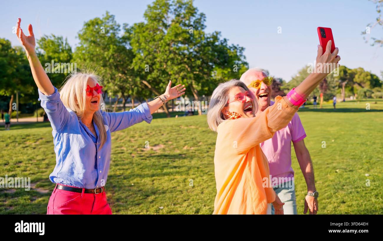 Des seniors profitant d'un selfie amusant en plein air avec des lunettes de soleil colorées Banque D'Images