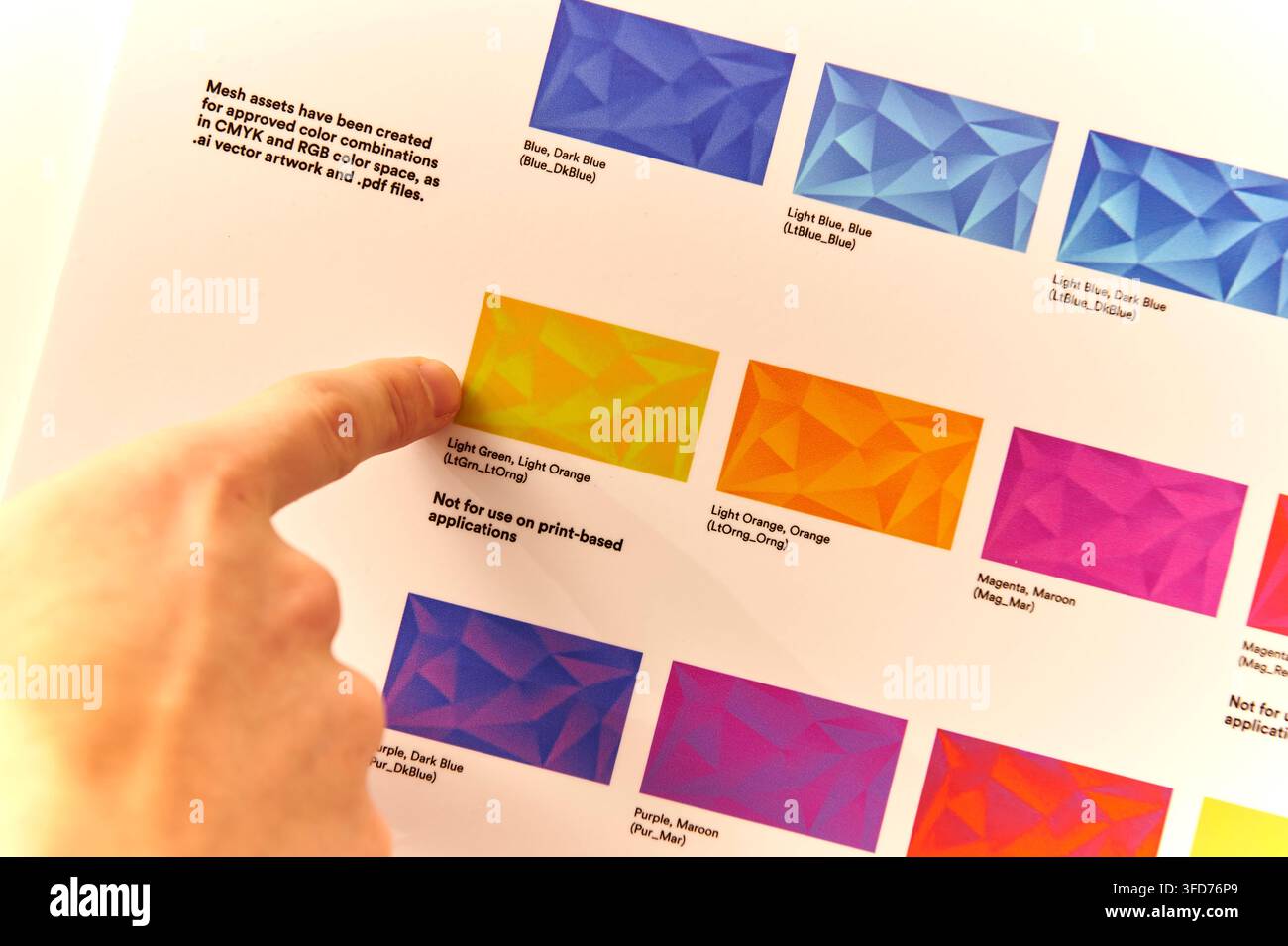 Gros plan d'un guide d'identité visuelle corporate 3M montrant des combinaisons de couleurs approuvées et des actifs de maillage graphique, avec un employé pointant une couleur Banque D'Images