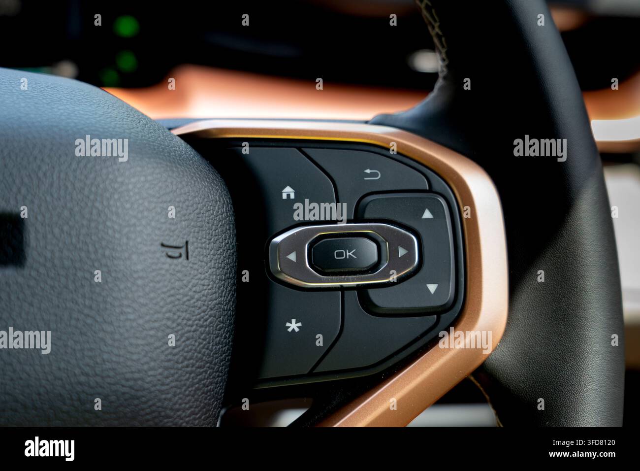 Grossissement des touches de navigation directionnelle et du bouton de sélection OK avec finition cuivrée sur un volant en cuir à l'intérieur d'une cabine de voiture moderne. Banque D'Images