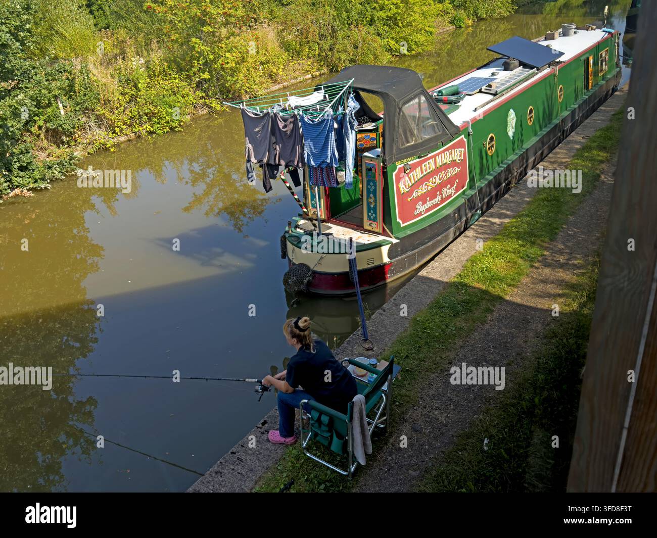 Scène de vie sur un bateau de canal avec pêche et lessive à côté d'un bateau étroit amarré. Banque D'Images