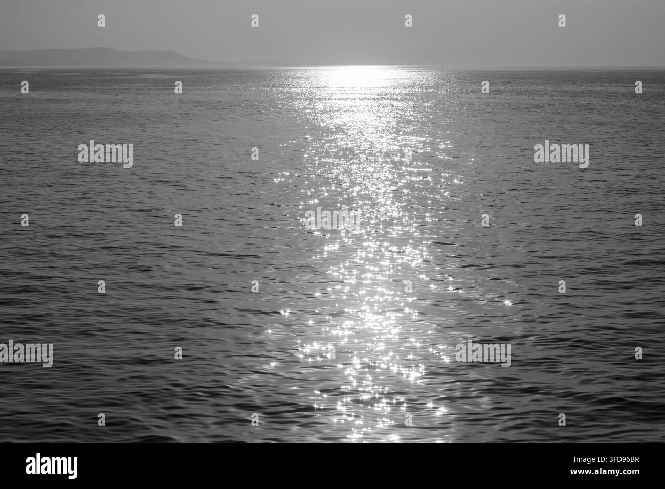 Une scène tranquille d'un vaste plan d'eau illuminé par les rayons du soleil, créant un effet radieux et cristallin sur la surface miroitante de l'eau Banque D'Images