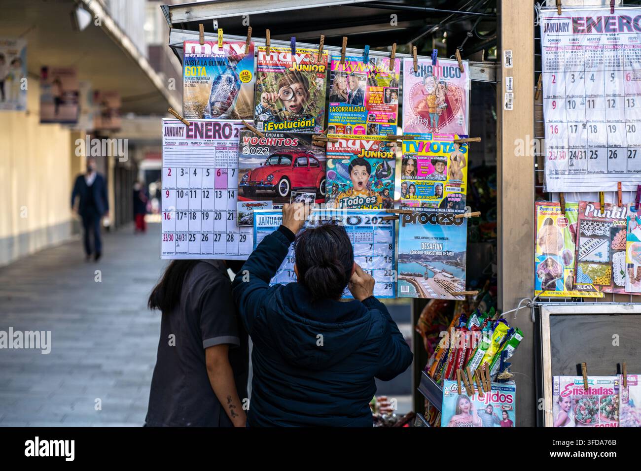 Mexico City Mexique - 15 février 2022 : Une femme accrochant un calendrier avec des magazines sur un kiosque à journaux à Mexico Mexique Banque D'Images