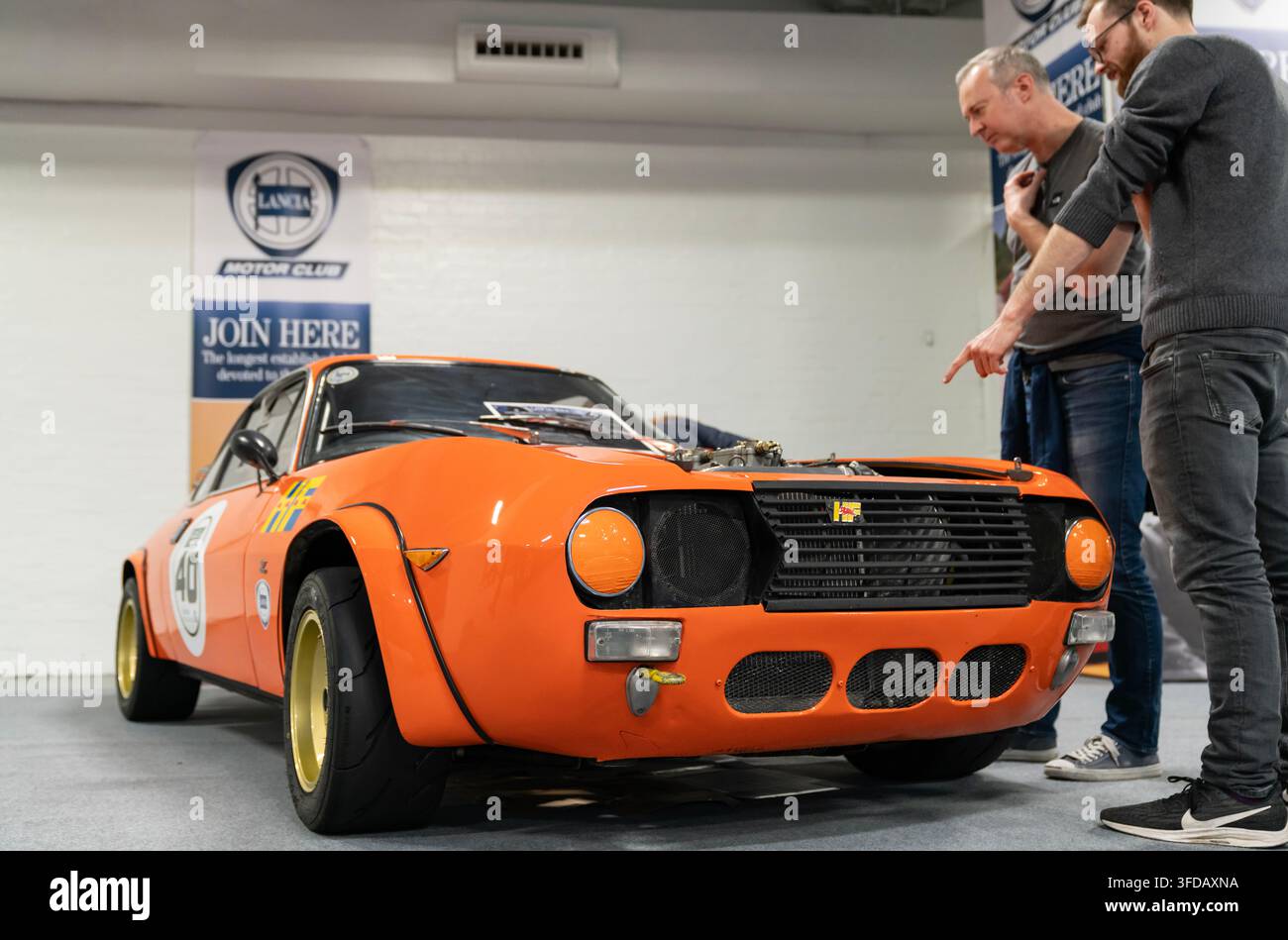 Londres, Royaume-Uni - 22 février 2020 : Des visiteurs examinent une voiture de compétition classique Lancia orange exposée lors d'une exposition automobile. Banque D'Images