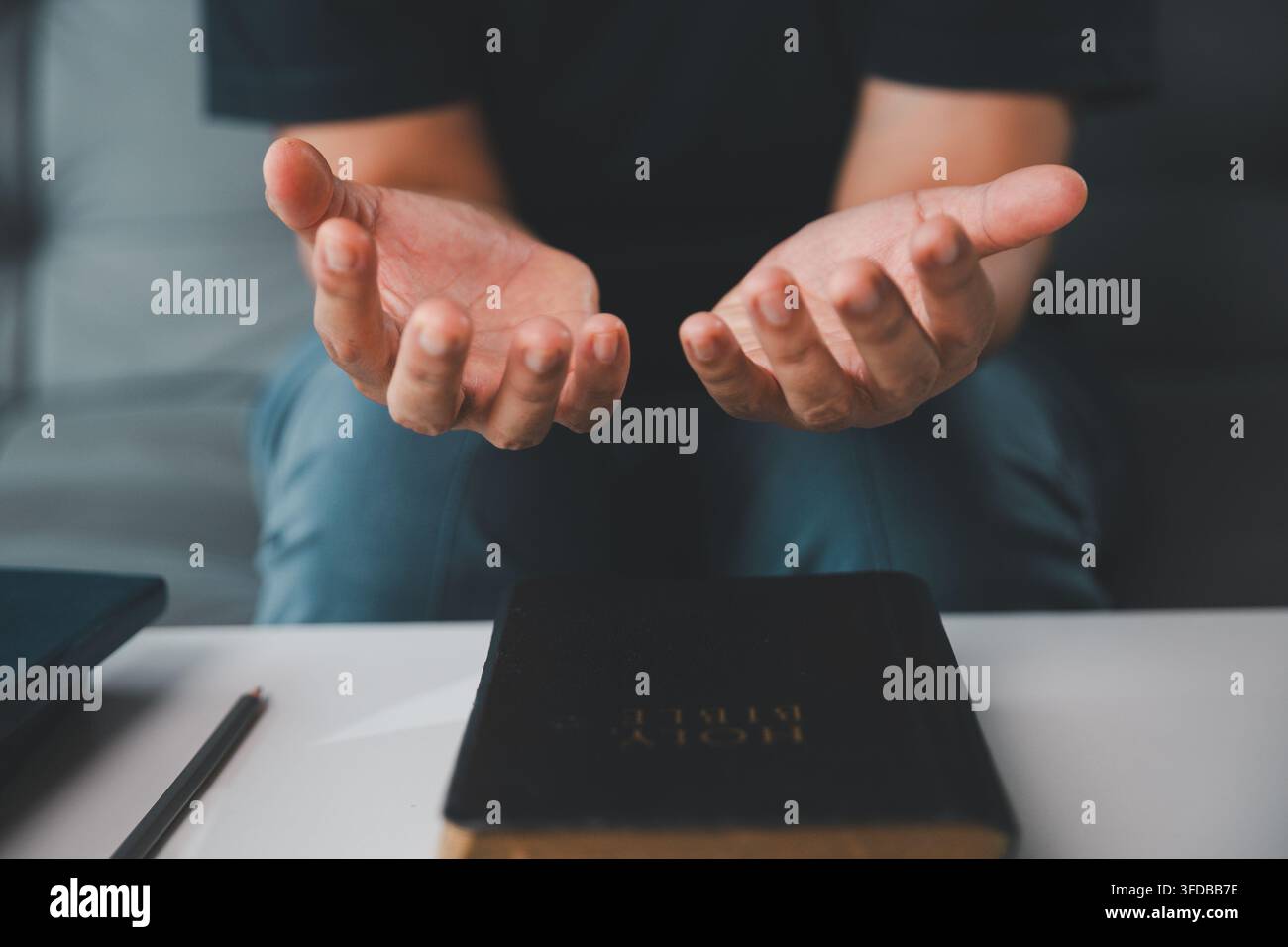 Close-up d'une femme tenant ses deux paumes ouvertes au-dessus d'une Bible lors de la prière, représentant l'adoration chrétienne, la soumission, la réception de la grâce, la gratitude, h Banque D'Images