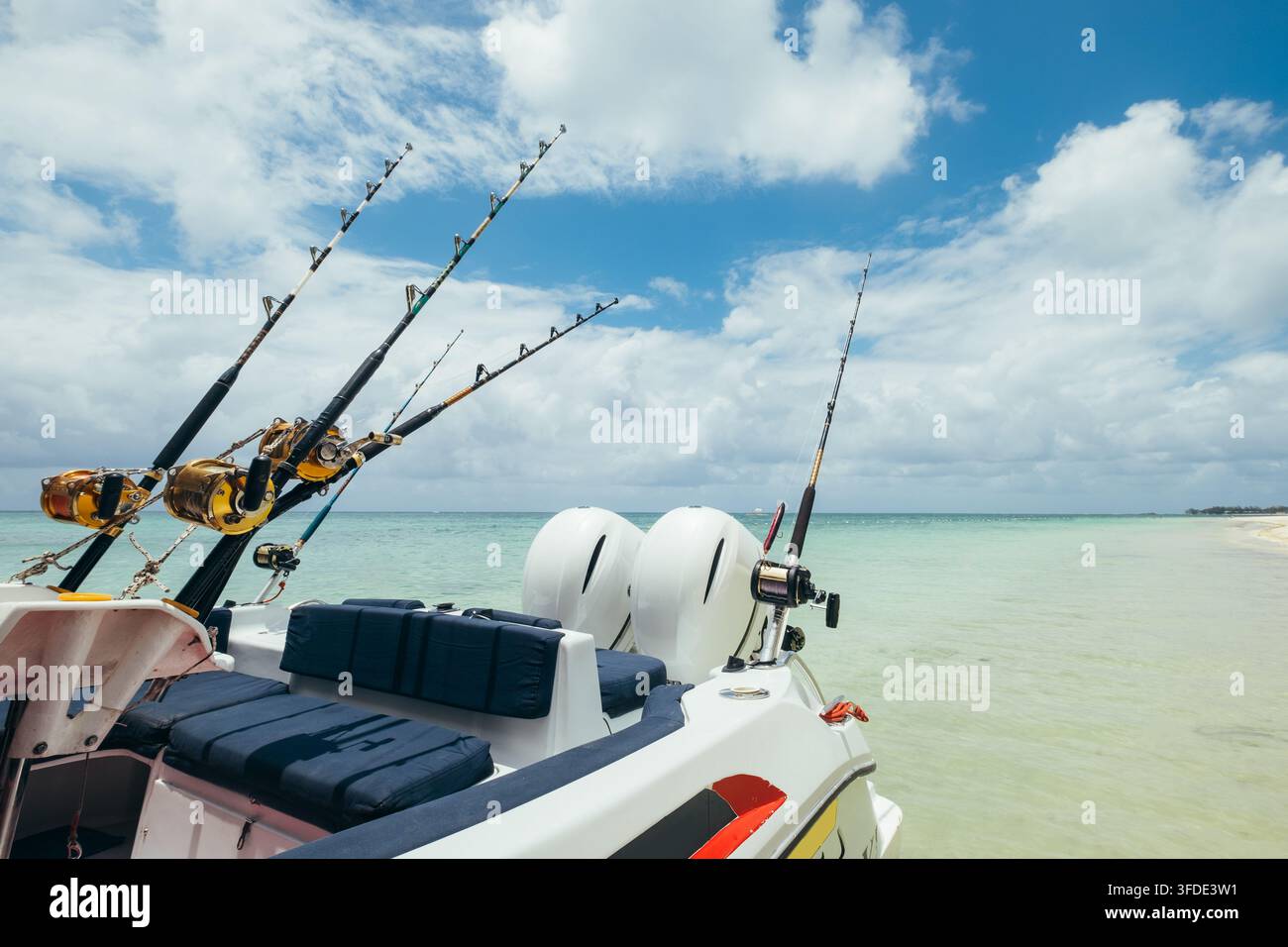 Cannes à pêche professionnelles avec moulinets robustes montés sur un bateau à moteur naviguant sur des eaux turquoise et calmes le long de la côte tropicale de l'île Maurice Banque D'Images