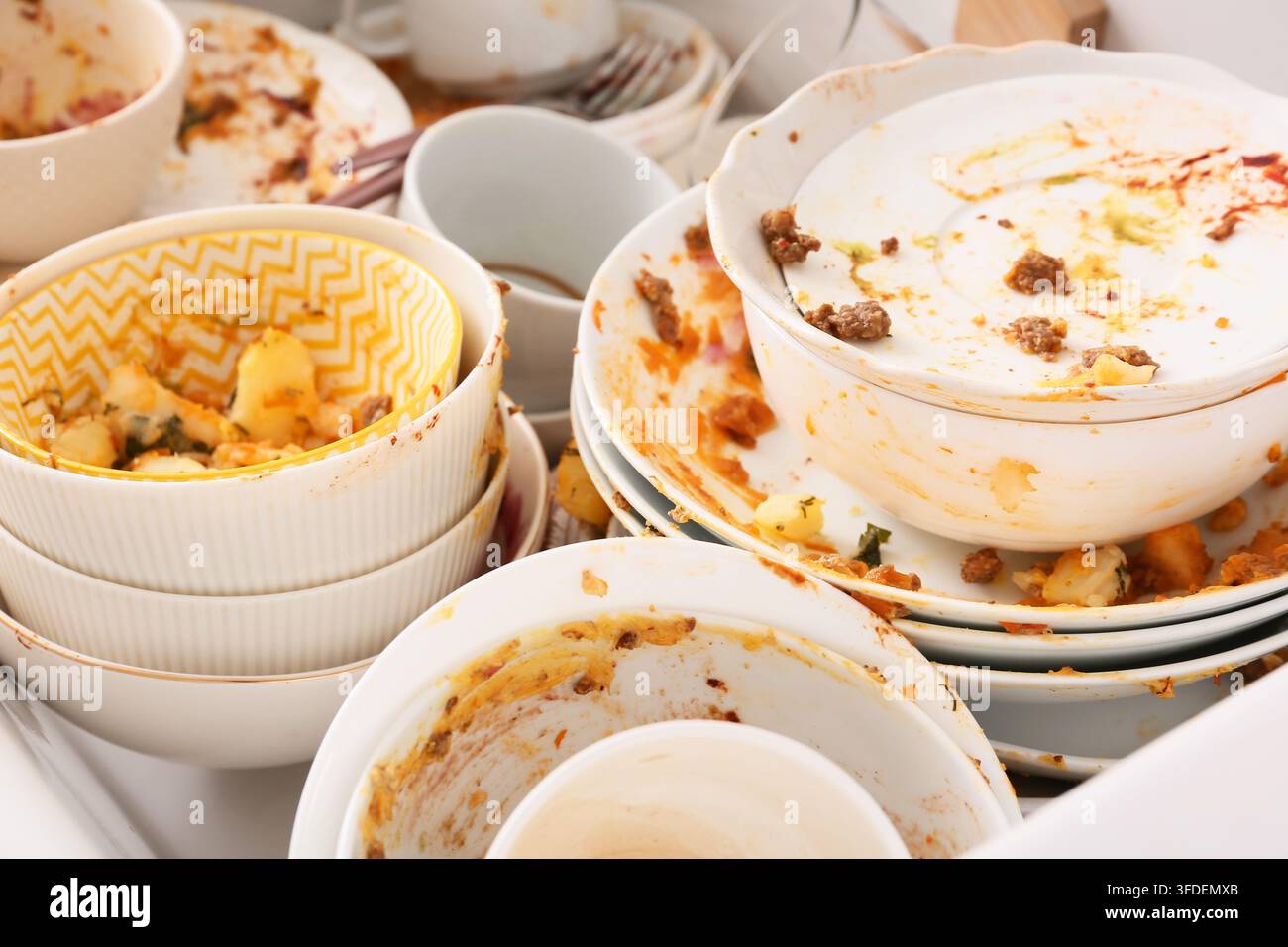Ménages domestiques et désordre domestique, pile de vaisselle sale et bols graisseux dans l'évier de la cuisine après un dîner avec des restes de nourriture et des déchets alimentaires Banque D'Images