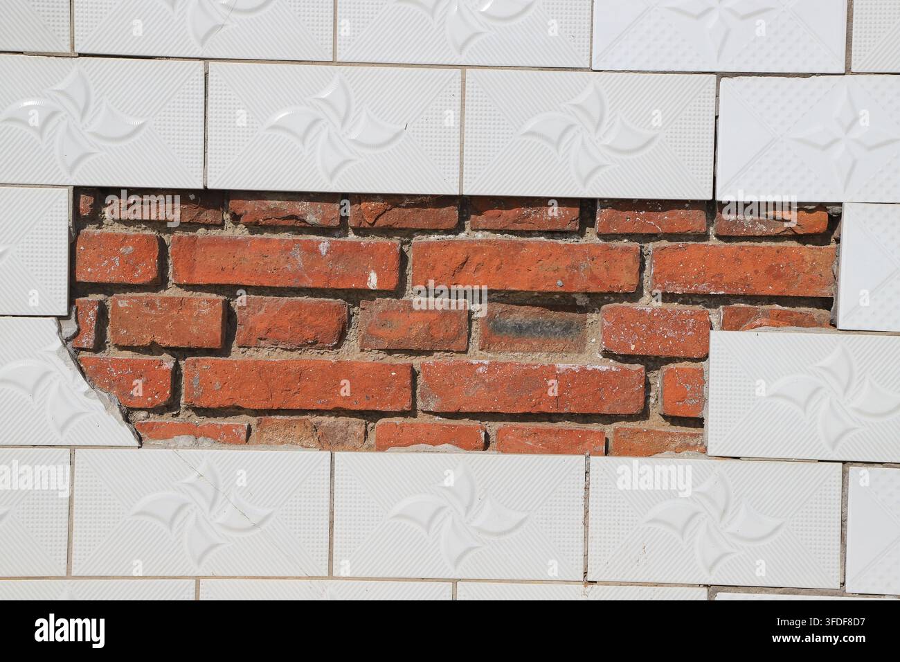 Un contraste frappant est formé par le revêtement de carreaux de céramique à motifs géométriques blancs et le mur de briques rouges apparent. D'un côté, il y a un moderne soigné Banque D'Images