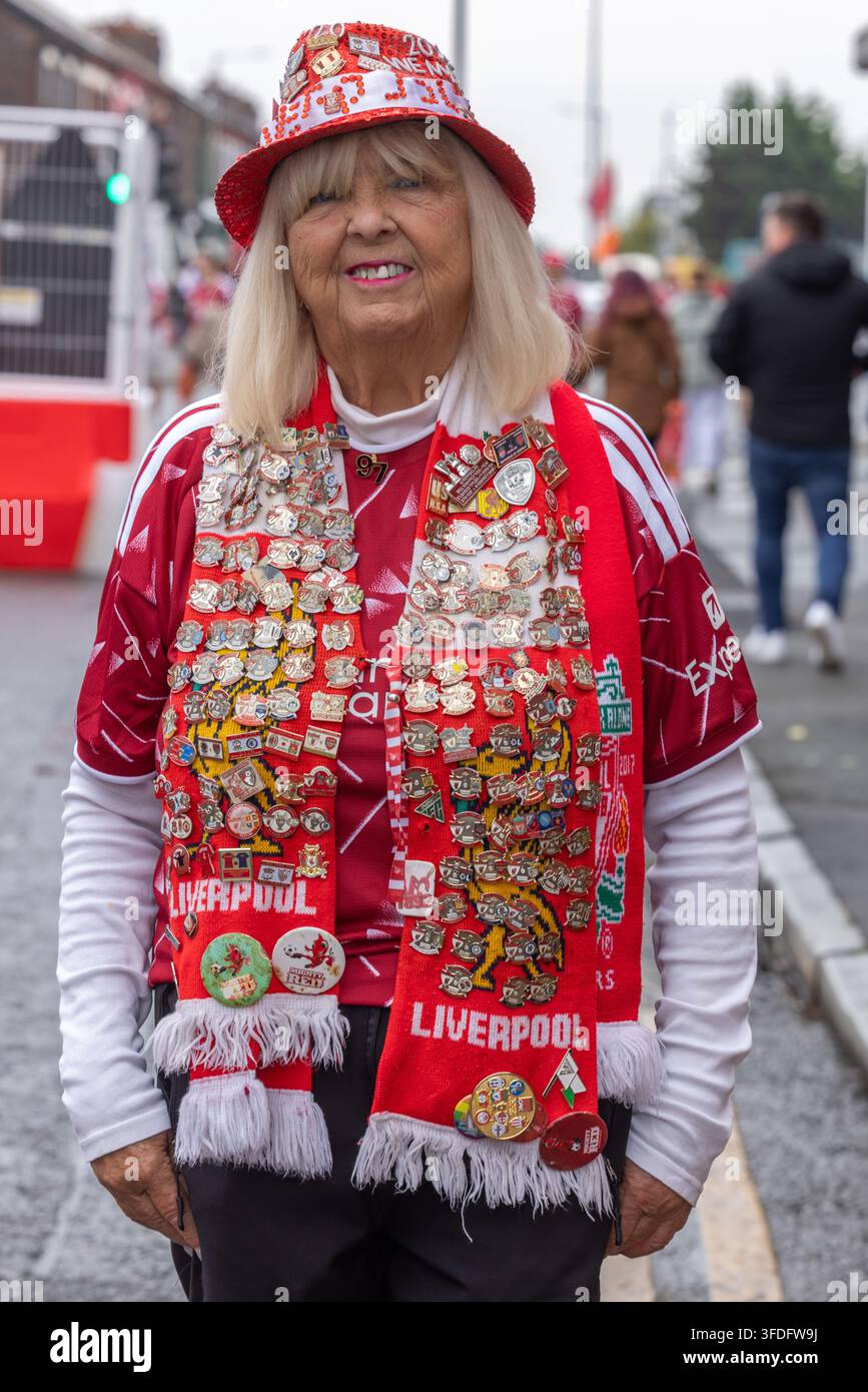 Anfield, Royaume-Uni. Une fan senior du Liverpool F.C. montre fièrement son immense collection de badges du club qui recouvrent son chapeau de match et ses écharpes. Banque D'Images