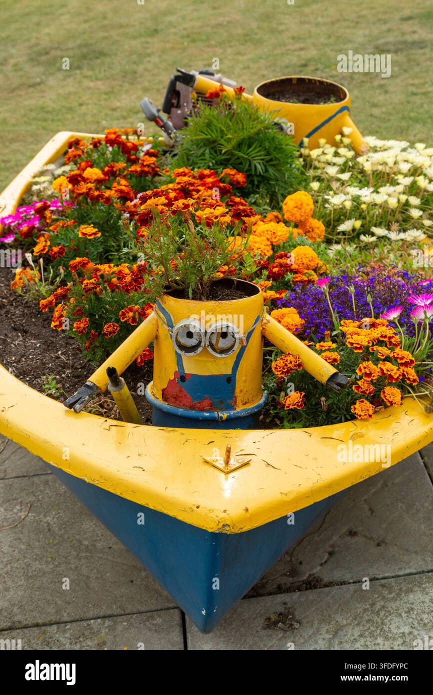 Un pot de jardin en forme de bateau jaune et bleu avec un pot jaune en forme de personnage Minion au centre, East Wemyss, Fife, Écosse Banque D'Images