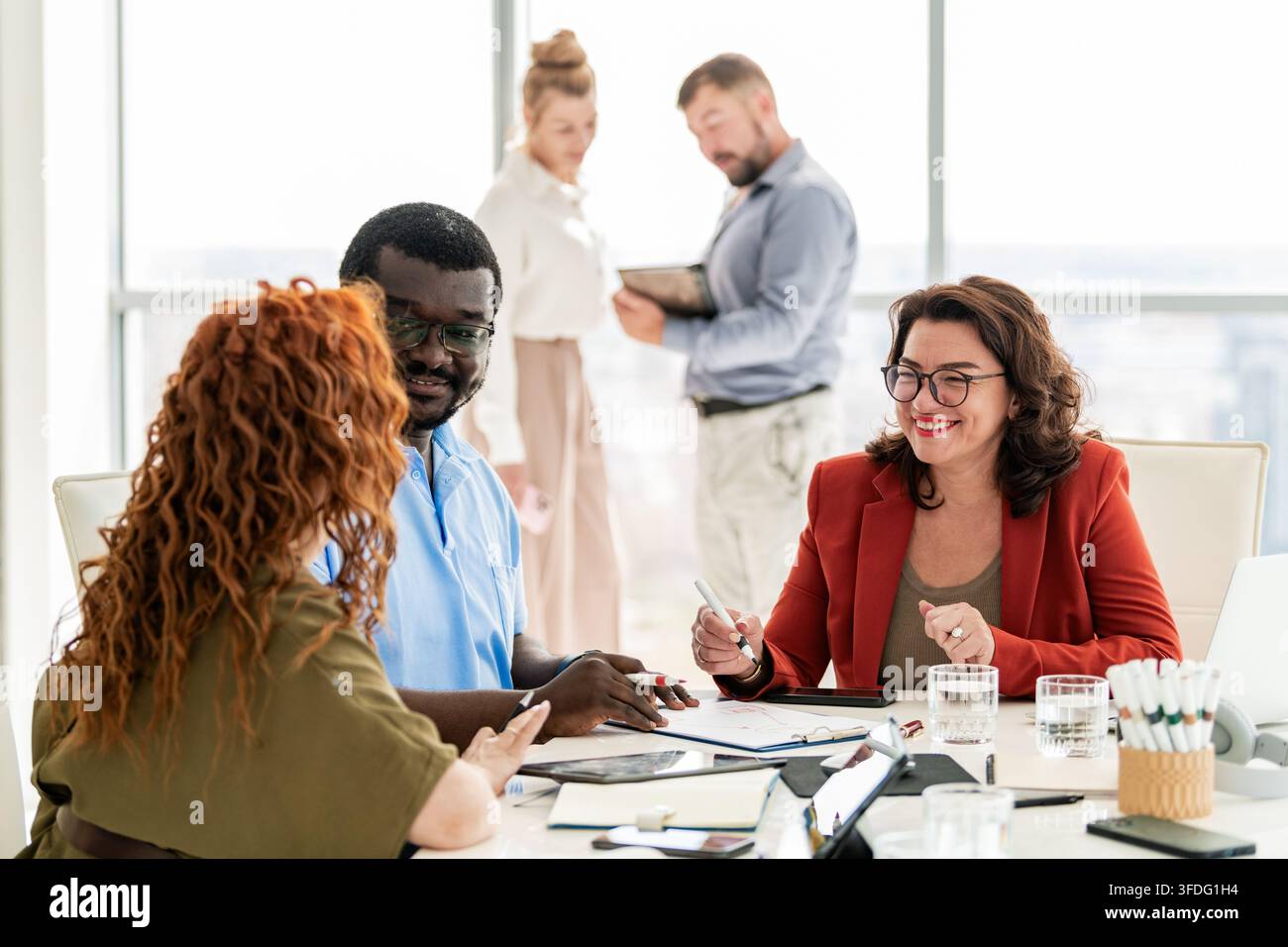 Collègues divers et heureux faisant un brainstorming dans un bureau lumineux Banque D'Images