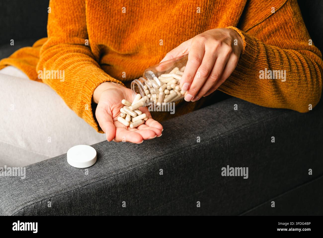 Femme versant des capsules de médicament d'une bouteille dans sa main Banque D'Images