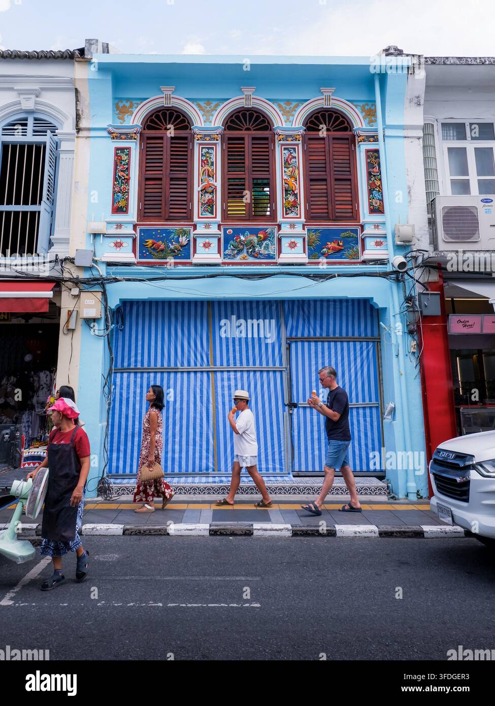 PHUKET, THAÏLANDE - 16 août 2026 : Les touristes marchent devant un bâtiment peint en bleu dans la vieille ville de Phuket Banque D'Images
