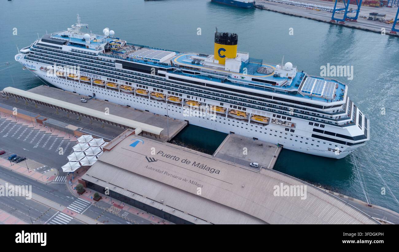 Paquebot de croisière luxueux amarré dans le vibrant port de Malaga, mettant en évidence plusieurs ponts, des piscines et des canots de sauvetage contre un fond de port pittoresque Banque D'Images